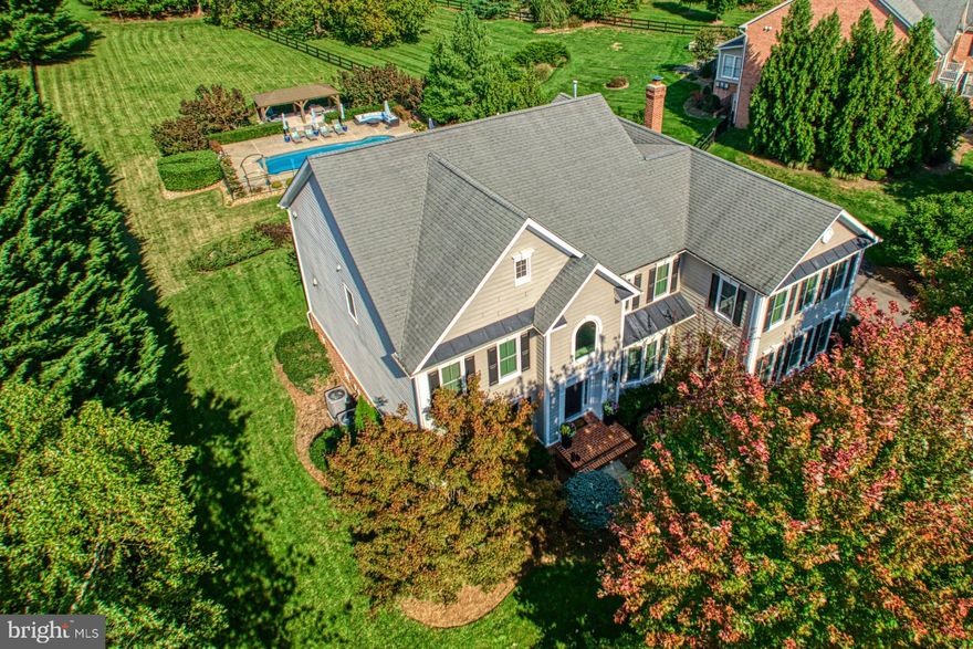 This idyllic Beacon Hill beauty welcomes, as traditional design and professional landscaping create sophisticated curb appeal for a thoughtfully crafted home. Within, 6,902 square feet are cream-colored and soft where pillars, shadow box detailing, thoughtful built-ins, and endless trimmings add architectural interest to rooms for gathering, work, and play. A cheerful escape with polished touches, you’ll enjoy both everyday living and holiday celebrations as hardwoods, sunny windows, and posh fixtures line a flowing floor plan. While guests enjoy sunroom views or the living room’s fieldstone fireplace, the chef can be the life of the party - offering tastes of nearly finished recipes and gossiping with guests from the newly renovated centerpiece kitchen. Here, gorgeous illuminated cabinetry, quartz countertops, and high-end appliances complete the home’s heart. In the lower level, add favorite local wines to your onyx-hued 500+ bottle rack, host overnights in the full guest suite, and crown ping pong or pool champions. Outside, summer BBQ’s spread from the lightscaped deck to the pool where you’ll relax under the cabana and linger late to roast marshmallows ‘round the fire pit. In winter, nearly an acre of snow-covered views create a backdrop for coco and coffee. Five bedrooms, each with an en suite bath, refresh and soothe. In the primary, get cozy near your peninsula fireplace, and step into your dressing destination where dual closets and a chic bathroom awaits. Here, luxe hardware and modern tiling add texture, while the graceful free-standing tub invites you to unwind. While on tour, visit the three car garage and ask about additional upgrades. From home, morning runs along neighborhood trails promise wildlife sightings, while commuter and adventure routes lead to historic townships, Leesburg shops and dining, electric OneLoudoun, Dulles International Airport, and all Hunt and Wine Country has to offer