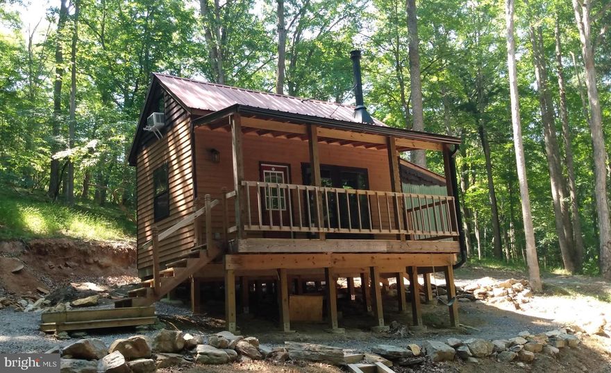 The Perfect Get-A-Way cabin is waiting for you Now!  setting on 8.30 acres with Cacapon River Access within a stones throw. This Tiny Cabin is off the grid, with solar and generator power, composing toilet, the owner brings water with him, but with the new metal roof it would be a perfect situation for a cistern. Electric is nearby, should the new owner desire hook up. This is a high quality  build with -  Cedar siding and eaves. Cypress trim and gable, Anderson windows, wood doors and trim, live oak counter tops that are lacquered.  Waterproof luxury vinyl plank flooring, woodstove rated for 1100 sq. ft.,  The furniture conveys and will sleep six. The drive and parking areas are blue stone and there is a 8 x 16 shed that is sided in Hardie Plank.  Enjoy the the river or just unwind on the covered porch. Oh! target shooting and hunting are fine and these 8 acres are great for it. Make your appointment today!