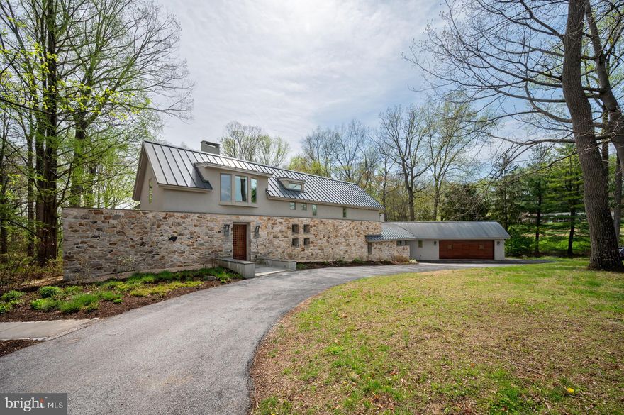 A stone façade rises from the landscape as if it has always belonged there, framed by meticulously composed gardens that feel less designed and more discovered. Before you ever cross the threshold, the tone is set: this is a home shaped by intention, care, and a quiet reverence for its surroundings.
Set on two private acres in the rolling countryside of Chester County, this 4,342-square-foot residence was taken down to its bones and reimagined in 2015. What emerged is not simply a renovation, but a transformation guided by a modern European sensibility—where proportion, material, and light were considered as essential elements of the design. Nothing here feels applied; everything feels inherent.
Oversized windows act as living canvases, drawing in open sky, mature trees, and the shifting colors of the fields beyond. The home breathes with its environment—expansive yet grounded, refined yet deeply connected to nature. Just across the way, access to Cheslen Preserve extends this experience even further, offering hundreds of acres of protected woodland as part of your daily rhythm.
At the heart of the home, the kitchen unfolds as both anchor and gathering place. It is where life naturally converges—generous in scale, thoughtful in function, and seamlessly connected to the spaces around it. Custom walnut cabinetry, designed by the owners, brings a richness and depth that feels both grounded and refined, striking a balance between warmth and restraint. Underfoot, Carlisle white oak floors lend a quiet authenticity, complemented by Caesarstone Quartz surfaces that add texture and permanence. Four wood-burning fireplaces introduce a sense of ritual and comfort. Every detail—from Wolf and Sub-Zero appliances to the butler’s pantry and oversized secondary pantry—supports both everyday living and effortless entertaining.
From this central space, the home opens naturally in multiple directions. The living room, family room, and private office each offer their own perspective on the surrounding landscape, with views that draw the eye outward toward the patio and gardens beyond. Two powder rooms, a mudroom, and abundant storage are integrated with ease and discretion, preserving both function and flow.
Upstairs, three bedrooms and two full baths continue the home’s calm, cohesive tone. The primary suite feels like a retreat unto itself, with a spacious bath where a soaking tub is positioned to take in garden views—a quiet moment suspended between indoors and out. A walk-in closet completes the suite with both beauty and practicality.
The lower level is thoughtfully divided into two distinct functional areas. One side offers a finished room ideal for a gym or studio with generous storage. The other is located just six steps from the kitchen and includes a clean, well-appointed laundry space seamlessly integrated into daily circulation.
Even the garage carries intention, with its oversized footprint and custom cherry door adding a final note of craftsmanship.
Outside, the landscape unfolds as its own work of art. Designed by the owner, GreenWeaver Landscapes and Pinwheel Landscaping in 2022, the grounds are sculpted with Corten steel and Pennsylvania bluestone forming patios, pathways, and terraces that feel organic to the land. Waterfalls trace their way down stone steps into a naturalized garden where structure gives way to softness. Planted with care but never rigidity, the garden invites wandering, observation, and a sense of quiet discovery.
There is no HOA. No compromise. Only a home that feels both composed and alive.
Located within the award-winning Unionville-Chadds Ford School District and just minutes from the vibrant dining and cultural scene of Kennett Square, this is a place where design, nature, and daily life exist in rare harmony.
Built in 1978. Transformed with purpose. Now ready for its next chapter.
