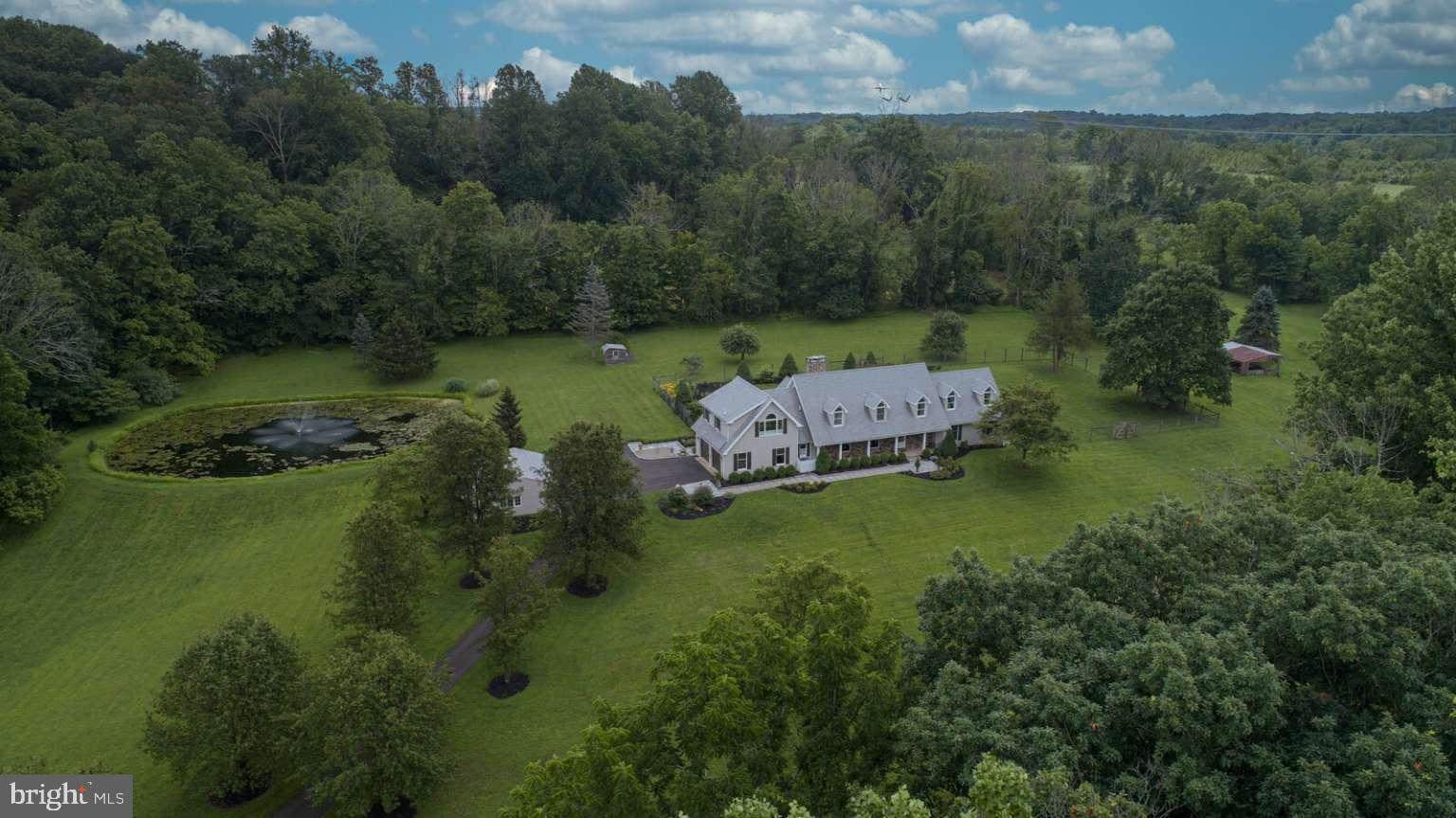 Live the lifestyle in this quintessential Solebury home in coveted Carversville, Bucks County. Cross over the Paunnacussing Creek on the newly restored bridge to enter the tree-lined driveway. Privacy abounds around the 4064 sq. ft. home including 12 acres with pond and a large, protected farm directly behind the tree-lined property. The large, deer-fenced and level back yard has plenty of room to entertain family and friends, let dogs run freely, and/or put in a large pool. Enjoy an evening under the stars or around the EP Henry Fire pit on the slate patio.
The property is under Act 319 (Clean & Green 10+ acres) and can accommodate up to 7 horses. The property includes an attached 2-car garage, detached 2-car garage with new garage doors/openers, shed, hen house and barn area. The pond is spring fed, includes a timed fountain and is stocked with large-mouth bass for hours of pleasure with the family.
The home has been completely renovated including a new roof and landscaping. The move-in ready, open concept floor plan, a Kitchens By Charles Weiler design, includes a newly remodeled kitchen and bathrooms. The kitchen includes high-end finishes such as an integrated Sub-Zero refrigerator, Wolf gas range, Miele convection steam oven, Bosch dishwasher, marble butterfly-patterned backsplash, and 16 ft. marble island with 5-foot Galley brand sink that includes 2 touchless faucets and accessories (cutting boards, drain boards and colanders). The laundry room includes a Bosch washer and dryer, lots of counter space and second refrigerator.
The main floor is open and spacious with plenty of dining and entertainment options. Arrange chairs or tables around the double-side stone fireplace for cozy gatherings or large parties. The unique bar has a custom metal-riveted countertop and loads of storage. Take the front or back staircase to reach 3 large bedrooms, hall bathroom, and a very large primary suite. The primary bathroom is taken straight out of a luxury hotel with 6’ free standing soaking tub, shower with digital controls, rain head, and custom vanity with large make-up area.
The expansive great room has exposed beams, custom chandeliers, plenty of room for the 120” theater with built-in sound system and custom window treatments. With the 5 zone baseboard hot water heat and 2 zone central HVAC, you can control the temperature and cost on-demand. The finished basement includes another fireplace, home gym area, and temperature-controlled 200-bottle wine cellar. Go through another set of doors to enter your large workshop area with work benches, plenty of room for storage and access to the back yard through Bilco doors.