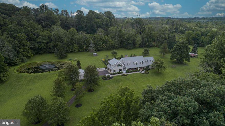 Live the lifestyle in this quintessential Solebury home in coveted Carversville, Bucks County. Cross over the Paunnacussing Creek on the newly restored bridge to enter the tree-lined driveway. Privacy abounds around the 4064 sq. ft. home including 12 acres with pond and a large, protected farm directly behind the tree-lined property. The large, deer-fenced and level back yard has plenty of room to entertain family and friends, let dogs run freely, and/or put in a large pool. Enjoy an evening under the stars or around the EP Henry Fire pit on the slate patio.
The property is under Act 319 (Clean & Green 10+ acres) and can accommodate up to 7 horses. The property includes an attached 2-car garage, detached 2-car garage with new garage doors/openers, shed, hen house and barn area. The pond is spring fed, includes a timed fountain and is stocked with large-mouth bass for hours of pleasure with the family.

The home has been completely renovated including a new roof and landscaping. The move-in ready, open concept floor plan, a Kitchens By Charles Weiler design, includes a newly remodeled kitchen and bathrooms. The kitchen includes high-end finishes such as an integrated Sub-Zero refrigerator, Wolf gas range, Miele convection steam oven, Bosch dishwasher, marble butterfly-patterned backsplash, and 16 ft. marble island with 5-foot Galley brand sink that includes 2 touchless faucets and accessories (cutting boards, drain boards and colanders). The laundry room includes a Bosch washer and dryer, lots of counter space and second refrigerator.

The main floor is open and spacious with plenty of dining and entertainment options. Arrange chairs or tables around the double-side stone fireplace for cozy gatherings or large parties. The unique bar has a custom metal-riveted countertop and loads of storage. Take the front or back staircase to reach 3 large bedrooms, hall bathroom, and a very large primary suite. The primary bathroom is taken straight out of a luxury hotel with 6’ free standing soaking tub, shower with digital controls, rain head, and custom vanity with large make-up area.

The expansive great room has exposed beams, custom chandeliers, plenty of room for the 120” theater with built-in sound system and custom window treatments. With the 5 zone baseboard hot water heat and 2 zone central HVAC, you can control the temperature and cost on-demand. The finished basement includes another fireplace, home gym area, and temperature-controlled 200-bottle wine cellar. Go through another set of doors to enter your large workshop area with work benches, plenty of room for storage and access to the back yard through Bilco doors.