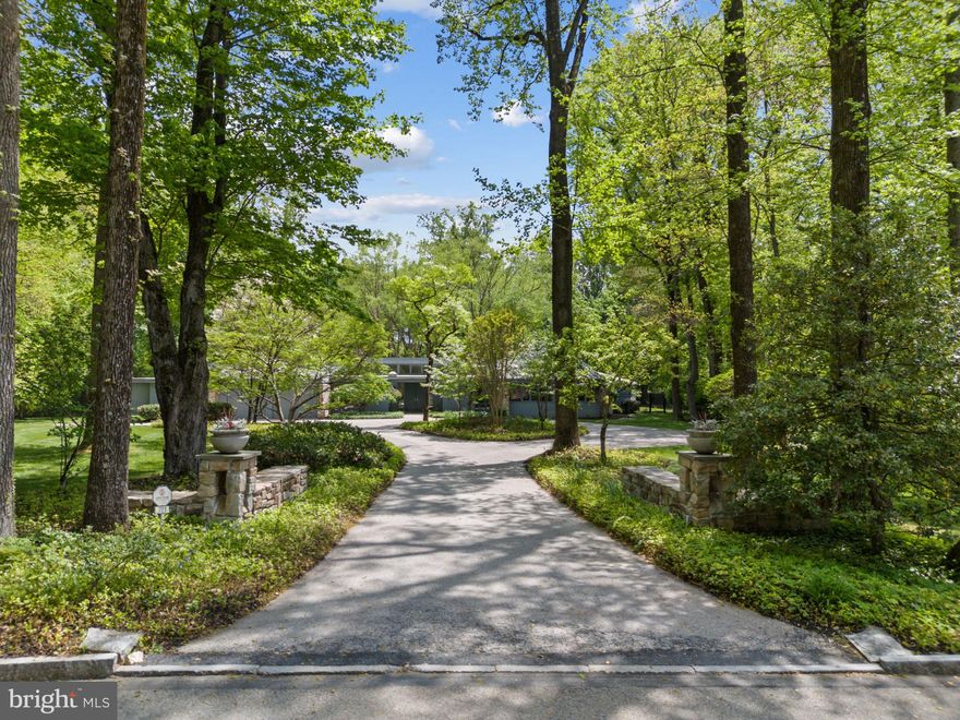 Welcome to 721 John Barry Drive, an elegant and expansive home nestled in the heart of prestigious Lower Merion Township. Set on a lush, meticulously maintained two-acre lot, this residence offers refined living inside and out—with beautifully landscaped grounds, resort-style amenities, and a layout ideal for both entertaining and everyday comfort. A gracious circular driveway welcomes you to this serene retreat framed by mature trees and specimen plantings.
Step inside to discover a bright and open floor plan accented by hardwood floors, recessed lighting, and thoughtful architectural details throughout. A wall of mirrored closets and a stylish powder room greet you at the entry. Just beyond, the sunken living room impresses with vaulted ceilings, a striking floor-to-ceiling stone fireplace, and expansive windows offering uninterrupted and breathtaking views of the scenic backyard.
To the left of the entry, a formal dining room flows seamlessly into the hallway and living areas and features a custom built-in table with seating for ten—plus additional leaves for expansion, making entertaining effortless.
At the heart of the home is a chef’s kitchen designed for both beauty and performance. Outfitted with granite countertops, a circular serving peninsula, abundant custom cabinetry, and high-end stainless appliances—including a six-burner Wolfe stove, Bosch dishwasher, Miele ovens, Whirlpool compactor, and Sub-Zero refrigerator—this kitchen meets every culinary need. A large main sink is complemented by a secondary prep sink, while the kitchen also offers direct access to the two-car garage and the backyard.
Adjacent to the kitchen, the light-filled family room features a second fireplace, skylights, and serene backyard views, with direct access to a screened-in porch for enjoying quiet mornings or warm summer evenings. A spacious office just off the family room offers built-in storage, a sink, and walkout access to the rear yard—ideal for remote work or creative pursuits. The lower level, accessed off the kitchen, provides abundant additional storage and room for future customization
One of several thoughtful additions to the home includes an expansive multipurpose room—once an art studio, now a flexible space that could serve as an enormous great room, gym, or game room, all with panoramic views of the backyard.
Through to the opposite wing of the kitchen, you’ll find a large pantry, a skylit laundry room, a storage closet, and an additional door to the driveway. A private fifth bedroom suite is located here—perfect for guests or multigenerational living.
Back at the front hall, turn right to discover a handsome wet bar alcove and a richly appointed library with a full wall of custom built-ins and pocket doors for added privacy.
The bedroom wing features the primary suite with generous customized closet space, shower and soaking tub and door to rear yard access.  Three additional ensuite bedrooms are positioned nearby, all designed to maintain privacy..
Step outside to a backyard oasis. The area between the house and the pool is elegantly hardscaped and accented by a cluster of River Birches, creating a tranquil transition to the resort-like amenities beyond. Enjoy a full-size tennis court, a sparkling swimming pool, and a well-equipped pool house complete with two full bathrooms, changing rooms, and a kitchenette—everything you need to entertain in style.
721 John Barry Drive offers a rare combination of luxury, flexibility, and natural beauty—all in one of the Main Line’s most coveted neighborhoods. This is a home that invites you to live expansively and comfortably, surrounded by timeless elegance and modern convenience.