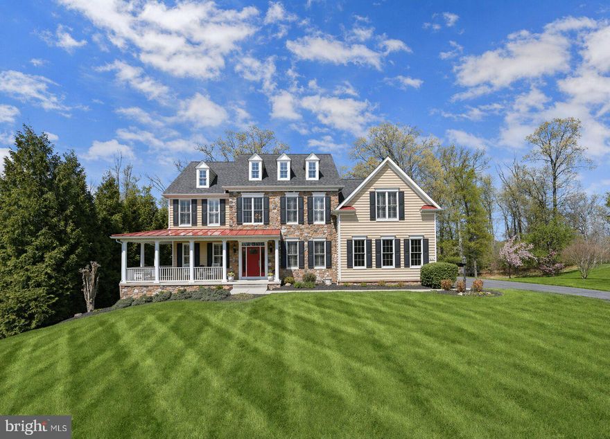 Welcome to 2410 Ellies Way, a stunning Catonsville Homes Lexington model offering exceptional craftsmanship, elegant design, and luxurious living across every level. Set on a picturesque 1.18-acre private lot backing to trees and tucked on a quiet cul-de-sac street, this original-owner home has been meticulously maintained throughout. From the charming covered wrap-around front porch to the striking stone façade and red metal roof accents, the curb appeal makes a lasting impression. Inside, you’ll find 9-foot ceilings on all levels, including a fully finished walk-out basement, and a dramatic 12-ft coffered ceiling in the family room, highlighted by transom windows and a beautiful masonry gas fireplace with stone surround and raised hearth. Gleaming hardwood floors span the main level, complemented by an open, flowing layout with formal living and dining rooms featuring crown molding, chair rail, tray ceiling, and architectural columns. The gourmet kitchen is a true centerpiece, featuring granite countertops, 42” designer cabinetry with crown molding, a spacious island with storage & drawers, and premium stainless steel appliances including a GE Profile double wall oven, 5-burner cooktop, Bosch dishwasher, and LG refrigerator. A large walk-in pantry, under-cabinet lighting, and planning station add functionality, while the adjoining morning room fills the space with natural light. Step outside to the screened-in porch with Trex decking and ceiling fan, perfect for enjoying the outdoors even on the hottest or rainiest days, with additional deck space ideal for grilling and stairs leading to the patio below for seamless indoor-outdoor living. The main level also includes a private study with glass French doors and transom windows, a mudroom with built-in cubbies and ceramic tile flooring, a laundry room with an LG front-load washer and dryer, and a powder room. Upstairs, four spacious bedrooms include a luxurious owner’s suite with crown molding, two walk-in closets, a dressing area, and a versatile sitting room ideal for a home office or relaxation space. The renovated spa-inspired primary bath features a standalone soaking tub, dual vanities, a large shower, and a private water closet. Additional bedrooms include a Jack-and-Jill bath and a private en-suite, all with upgraded finishes. The fully finished lower level is designed for both entertaining and everyday living, offering a dedicated theatre room with a 120” screen, surround sound system, custom built-ins, and six leather reclining seats. Additional spaces include a large recreation area, gym with vinyl wood flooring, and a bonus craft/playroom with built-ins, along with walk-out access to a covered patio.
A three-car side-entry garage with insulated carriage-style doors, wall storage system, and Tesla electric vehicle charger completes the home. This home is thoughtfully equipped with energy-efficient features, including double-hung Anderson windows, natural gas heating, high-efficiency “90 Plus” gas furnaces, and two-zone heating and air conditioning for optimal comfort. A new premium impact-resistant roof with a lifetime transferable warranty adds peace of mind. Additional upgrades elevate this home even further, including a Control4 Smart Home Lighting System with programmable lighting, whole-home control, and integrated theatre system operation, as well as automatic thermostats. A Generac 20kW natural gas generator provides reliable backup power, while a Thompson Creek maintenance-free front door, AquaPro water filtration, an acid neutralizer system, and a Hydrotech water softener add to the home’s efficiency and convenience. Ideally located with easy access to major travel routes, this exceptional property offers the perfect combination of luxury, functionality, and modern convenience, all in a serene, private setting that can be enjoyed year-round, from vibrant fall colors to peaceful summer evenings filled with fireflies.