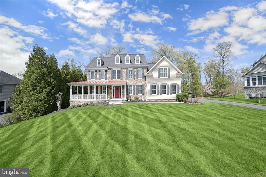 Welcome to 2410 Ellies Way, a stunning Catonsville Homes Lexington model offering exceptional craftsmanship, elegant design, and luxurious living across every level. Set on a picturesque 1.18-acre private lot backing to trees and tucked on a quiet cul-de-sac street, this original-owner home has been meticulously maintained throughout. From the charming covered wrap-around front porch to the striking stone façade and red metal roof accents, the curb appeal makes a lasting impression. Inside, you’ll find 9-foot ceilings on all levels, including a fully finished walk-out basement, and a dramatic 12-ft coffered ceiling in the family room, highlighted by transom windows and a beautiful masonry gas fireplace with stone surround and raised hearth. Gleaming hardwood floors span the main level, complemented by an open, flowing layout with formal living and dining rooms featuring crown molding, chair rail, tray ceiling, and architectural columns. The gourmet kitchen is a true centerpiece, featuring granite countertops, 42” designer cabinetry with crown molding, a spacious island with storage & drawers, and premium stainless steel appliances including a GE Profile double wall oven, 5-burner cooktop, Bosch dishwasher, and LG refrigerator. A large walk-in pantry, under-cabinet lighting, and planning station add functionality, while the adjoining morning room fills the space with natural light. Step outside to the screened-in porch with Trex decking and ceiling fan, perfect for enjoying the outdoors even on the hottest or rainiest days, with additional deck space ideal for grilling and stairs leading to the patio below for seamless indoor-outdoor living. The main level also includes a private study with glass French doors and transom windows, a mudroom with built-in cubbies and ceramic tile flooring, a laundry room with an LG front-load washer and dryer, and a powder room. Upstairs, four spacious bedrooms include a luxurious owner’s suite with crown molding, two walk-in closets, a dressing area, and a versatile sitting room ideal for a home office or relaxation space. The renovated spa-inspired primary bath features a standalone soaking tub, dual vanities, a large shower, and a private water closet. Additional bedrooms include a Jack-and-Jill bath and a private en-suite, all with upgraded finishes. The fully finished lower level is designed for both entertaining and everyday living, offering a dedicated theatre room with a 120” screen, surround sound system, custom built-ins, and six leather reclining seats. Additional spaces include a large recreation area, gym with vinyl wood flooring, and a bonus craft/playroom with built-ins, along with walk-out access to a covered patio.
A three-car side-entry garage with insulated carriage-style doors, wall storage system, and Tesla electric vehicle charger completes the home. This home is thoughtfully equipped with energy-efficient features, including double-hung Anderson windows, natural gas heating, high-efficiency “90 Plus” gas furnaces, and two-zone heating and air conditioning for optimal comfort. A new premium impact-resistant roof with a lifetime transferable warranty adds peace of mind. Additional upgrades elevate this home even further, including a Control4 Smart Home Lighting System with programmable lighting, whole-home control, and integrated theatre system operation, as well as automatic thermostats. A Generac 20kW natural gas generator provides reliable backup power, while a Thompson Creek maintenance-free front door, AquaPro water filtration, an acid neutralizer system, and a Hydrotech water softener add to the home’s efficiency and convenience. Ideally located with easy access to major travel routes, this exceptional property offers the perfect combination of luxury, functionality, and modern convenience, all in a serene, private setting that can be enjoyed year-round, from vibrant fall colors to peaceful summer evenings filled with fireflies.