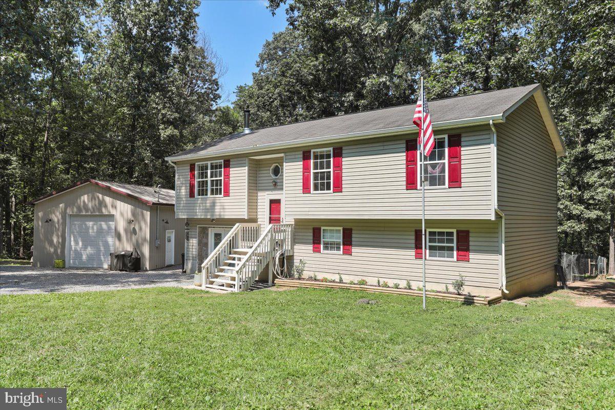 Welcome to this large split foyer style house (approx 1900 sq ft) with a detached garage, nestled on a lovely .87 wooded acre lot. There is no HOA and the roads are maintained by the department of transportation. No thru street for privacy! Stay cozy with a wood stove in the family room. Kitchen conveniences include an eating area, island , ceiling fan and pantry. Kitchen opens to a sliding glass door to a deck with stairs and to a fenced backyard. Lot backs to trees and is private..
Septic is for 3 bedrooms, but lower level offers a living room and three additional separate rooms which can be used for bedrooms/office/ crafts. Large laundry room with sink and commode. There is plenty of room to grow here! The detached one car garage has a separate electric meter and plenty of parking in driveway. Heat Pump 5 years old; xfinity internet; Conveniently located off Sulfur Springs rd with easy access to Inwood or Martinsburg.