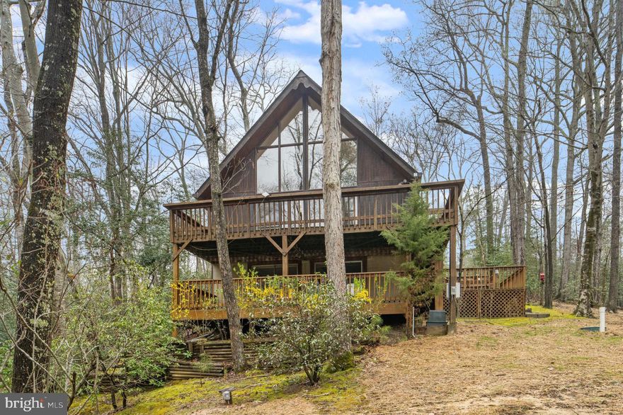 Tucked away like a storybook retreat in a private nature wonderland, this captivating A-frame home offers the perfect blend of charm, comfort, and lifestyle. Featuring 2 bedrooms and 2.5 baths, this home has been thoughtfully refreshed with new paint, luxury tile flooring, new carpet, and more—truly move-in ready.

Step inside to an open-concept floorplan highlighted by soaring cathedral ceilings and a loft that adds both character and flexible living space. Walls of windows flood the home with natural light and showcase serene views of the surrounding landscape from every angle, creating a seamless connection to nature.

Enjoy exclusive access to Lake Lariat, complete with a dock—perfect for kayaking, fishing, or simply relaxing by the water. Additional features include off-street parking and a brand-new septic system for added peace of mind.

Located in the highly desirable Chesapeake Ranch Estates (CRE) community, residents enjoy an exceptional range of amenities including a wooded campground, horseshoe pits, scenic hiking trails, private garden plots, and an athletic field. CRE also offers a dedicated Roads Department for year-round maintenance (including snow removal) and a roving Security Force.

Experience coastal living with access to two private sandy beaches along the Chesapeake Bay, as well as a large freshwater lake ideal for swimming, fishing, and sailing.

Convenience meets tranquility with the brand-new Lusby Town Center just one mile away, offering grocery shopping, fine restaurants, banking, the Lusby Post Office, and a variety of shops for everyday needs.

This is more than a home—it’s a lifestyle surrounded by nature, community, and modern convenience. Don’t miss this rare opportunity!