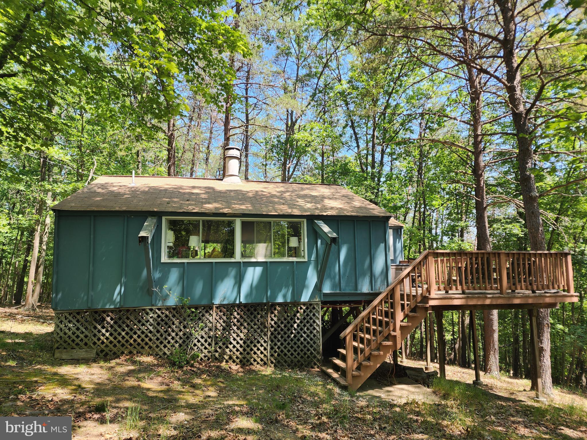 Cute cabin in the woods! Little slice of "almost Heaven" located on 2.2 acres in Sleepy Creek Hide-a-Ways! Small, 720 sq. foot cabin featuring a large great room with open concept and wood burning fireplace in the center. Surrounding the great room, there is a small kitchen, dining area, living space, loft, and adjoining primary bedroom and full bath with stall shower. This cabin would make a great weekend getaway from the hustle and bustle of the city - surround yourself with peace and privacy and the beautiful sounds of nature!