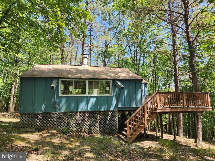 Cute cabin in the woods!  Little slice of "almost Heaven" located on 2.2 acres in Sleepy Creek Hide-a-Ways!  Small, 720 sq. foot cabin featuring a large great room with open concept and wood burning fireplace in the center.  Surrounding the great room, there is a small kitchen, dining area, living space, loft, and adjoining primary bedroom and full bath with stall shower.  This cabin would make a great weekend getaway from the hustle and bustle of the city - surround yourself with peace and privacy and the beautiful sounds of nature!