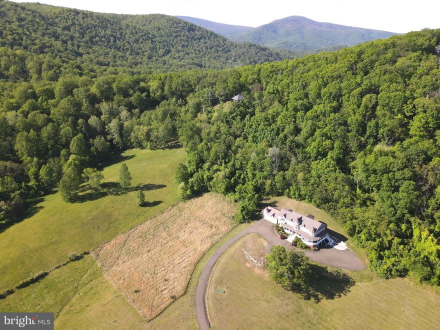 THE ROMANCE of an earlier era, LUXURIES of today and an EFFORTLESS sense of scale await on 29 acres with close by PANORAMIC VIEWS of the Blue Ridge Mountains, the surrounding embrace of the neighboring Shenandoah National Park in the day and the celestial Milky Way at night, all about an hour west of Washington DC.  This delightfully private estate feels less like a property and more like a hidden chapter.  Spectacularly spacious, delightfully livable and filled with ultimate comfort, this home  of roughly 9,600 sq ft unfolds with an effortless sense of scale, designed for living that stretches across generations.  *  Inside spaces are composed with intent.  Sunlit rooms invite slow mornings with coffee and books, fireside corners draw in conversation that lingers long past dusk.  A grand yet welcoming kitchen anchors the home, with generous dining and entertaining areas.  The family room becomes a heartbeat space, equally suited for family traditions, milestone toasts, and the easy chaos of everyone home at once.  A walkout level transforms into a spirited retreat of its own. A bar with kitchen sets the stage for evenings that drift between billiards, ping pong, the crescendo of a big game and laughter echoing just enough to remind you this house was built to be lived in, not tiptoed through.  ******  Six bedrooms are thoughtfully arranged to balance connection with privacy, including two separate private entrance apartments. One apartment attached to the garage offers an ideal two story escape where younger generations can carve out their own world within the larger frame.  The other apartment provides refined independence for your boomers who want to go to bed early and appreciate their own serene retreat.  * Think retirement. Think nature. Think work at home, for this office is more productive than any city office can possibly be. Think easy commute when you must go to town and a multi-generational home if so inclined.  This is not simply a home. It is a place where generations gather, scatter, and return again, each time adding another layer to its story.