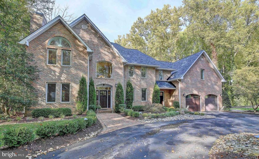 Located just minutes to Annapolis by road or waterway, down a non-thru tree lined road leading to the Severn River, sits an extraordinary property. This pristine home sits secluded on 3 acres with a shore line along Saltworks Creek and offers multiple boat slips.  The 4 sided brick home combines classic style and function making it perfect for large gatherings and intimate ones alike.  Brick pillars indicate the front entrance.  Extensive hardscaping and a water feature surrounded by the circular driveway lead to the front entrance. The flow of the main level boasts a timeless style of warm comfortable living.  The formal dining room and living room flank the 2 story entrance at the front of the home. The 2 story great room, gourmet kitchen, and home office are along the rear of the home offering majestic views of the acreage.  There is a pass thru bar between the living room and office. The kitchen's solid cherry cabinets offer organization solutions for every home chef, gorgeous granite, a gas range, multiple ovens, a wet sink, island with seating & 2nd sink, and stainless steel appliances & more.  The kitchen leads into a mudroom area hosting built-ins,  a pantry with a stackable laundry behind a pocket door, and garage access. Hardwood floors lead up the rear of the split stair case, into the owner suite and continue across the bridge to the 3 additional bedrooms each with en suite.  Owners suite offers a sitting area, separate custom closets, separate vanities, a jetted tub and cathedral ceiling.   A second laundry station with wash sink completes the upper level. Access the grand patio from the main level to admire the scenic views of the foliage and pier. The 130' pier offers to 2 aluminum boat lifts, 30 & 50 amp service, no maintenance composite decking, a tiki bar, tv and grill. The multi level stone patio offers multiple seating areas, a propane line for the grille master, and an oversized hot tub with a beautiful stone surround. A few steps down leads to the grand lower level that was just completed. Here one will find a custom bar like no other; the photos do not do it justice. The bar highlights Tennessee lumber, leather finished raw edge granite bar & counters, commercial refrigerator, stone tile backsplash, offering the stylish industrial vibe. A wine cellar is built into the wall across from the pool table. A 3rd gas fireplace is flanked by built-in bookcases and a custom mantle sit at one end of the great room while behind the barn doors is an exercise room and separate finished storage area. Completing the lower level is a half bath and an aupair or guest suite complete with a full bath, kitchenette, bedroom and private living space which continue the handsome design of the home. Additional 2020 improvements include a new roof and dual HVAC systems.  Additional features, solid brick construction, 2 story ceilings, tray ceilings, hardwood floors, planation shutters, constant pressure well pump, ceramic tile baths, blinds on remote, ceiling fans, oil rubbed bronze fixtures, recessed lights, neutral colors, pendant lights, ceiling fans, surround sound are just some of the features carried through the home.  All Tv's convey. 200+landscaping lights. Invisible fence.  Irrigation system & water feature.  All brick run-in shed with window, storage space in attic and wired for electric.