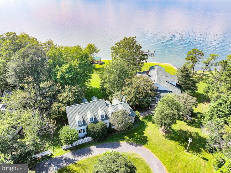 Step Back in time and experience the charm of  Eastern Shore living with this rare waterfront property overlooking the exciting waters of Eastern Bay. Set on 2.7 acres with secure and elevated shoreline, private dock, and powered boat lift, this estate offers the perfect balance of privacy, relaxation and endless potential.
The property features two dwellings with a combined total of six bedrooms, making it an ideal summer retreat or year round haven. The main house welcomes you with a striking 60-foot entrance hallway leading straight to the water, opening onto wide porches on every side- both open and screened- for seamless indoor-outdoor living. Cozy family room with wood burning fireplace adjoins country kitchen opening to screened porch and  great outdoor living. Upstairs brings you to a grand entertaining space that opens to a three season covered porch with breathtaking views of the bay and provides bunk space for family and friends.
Just steps away from the main house, the guest house provides additional comfortable living spaces. Designed to bring in natural light and water views it  offers useful , defined spaces  connected by light filled hallways Fully equipped kitchen and adjoined dining, living room, fabulous utility room and two generous bedrooms all with the same sweeping water views.
Shaded by mature planting, the grounds offer privacy and the natural beauty of the Eastern Shore, The property is further enhanced by a sturdy dock, charming potting shed, outdoor water-view shower and unique metal Gazebo close to the waters edge. Ample friendly parking and a circular driveway offer ease and a welcome entrance to the property.
Originally built in 1909 by the Rice family from Baltimore and used by the family for many years as a summer get away until sold in the 1970's .Subsequent owners continued the summer get away use , continual remodeling and updating  brought forth  numerous magazine features in Veranda, Country 
Life and the Baltimore Sun highlighting the clever use of space , style and the remarkable setting. This beloved property is ready for its next chapter. with a bit of updating, it can be restored to its full brilliance as a classic waterfront estate.