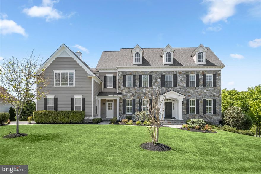 Discover luxury living in this extraordinary colonial nestled on a private corner lot spanning over an acre in the highly sought-after River Hill area of Fulton in Howard County. Originally the model home for the community, this exceptional residence showcases the highest level of sophistication, timeless architectural details, and endless opportunities for entertaining and everyday living with whole-house speakers. Arrive through the grand two-story foyer and experience a dramatic curved staircase, soaring ceilings, craftsman crown molding, box wainscoting, and gorgeous hardwood flooring that flows throughout the main level. The formal living and dining rooms elegantly welcome guests with custom ceiling details, plantation shutters, classic columns, chair railing, and refined box wainscoting. Beyond the private French door office accented by crown molding and double chair railing, discover a thoughtfully designed mudroom with built-in storage, a beautifully appointed laundry area, and access to the expansive three-car garage. The gourmet kitchen is the heart of the home, boasting a spacious center island with breakfast bar seating, abundant counter space, ceramic tile backsplash, 42” soft-close cabinetry with pull-out drawers, stainless steel appliances, and a bright breakfast area. The attached sunroom elevates the experience with designer ceiling details, elegant tile flooring, a built-in bar area, and direct access to the deck overlooking protected conservation views. The adjoining family room is equally impressive, featuring a modern gas fireplace surround, custom built-in bookcases, abundant natural light, and a tray ceiling accented with crown molding. A convenient back staircase provides seamless access to the upper level, where the luxurious primary retreat awaits. Designed as a tranquil, spa-inspired sanctuary, the primary suite offers a private sitting area with a wet bar and balcony access, plush carpeting, dual walk-in closets, a tray ceiling with crown molding, gas fireplace, in-ceiling speakers, and a lavish en-suite bath complete with soaking tub, separate vanities, water closet, and a double-entry walk-in shower with dual fixtures and stunning glass and ceramic accents. The upper-level south wing is thoughtfully designed with an ideal blend of bedrooms, baths, and workspaces, including two spacious bedrooms with walk-in closets connected by a dual-entry bath with double vanity and a custom desk area that separates the third bedroom and full bath. An additional private bedroom suite with a walk-in closet and en-suite bath completes the upper level. The fully finished lower level expands the living space with endless versatility, offering plush carpeting, a wet bar with dishwasher, a beverage cooler, and abundant storage. The custom wainscoted game area leads to a private bedroom, gym, and theater room. At the same time, the lounge with built-in seating opens directly to the patio and fire pit area for seamless indoor-outdoor entertaining. Ideally located near MD-32, US-29, and I-95, this remarkable residence provides convenient access to Washington D.C., Baltimore, Columbia Mall, Merriweather Post Pavilion, BWI Airport, and countless shopping, dining, and entertainment destinations.
