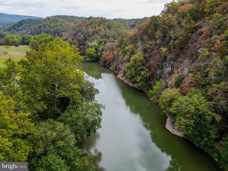 If you’ve been waiting for the perfect place to build your mountain escape, your opportunity is here. Tucked into the prestigious gated community of The Crossing at Great Cacapon, this 9.377-acre riverfront parcel offers a rare combination of privacy, peace, and potential. The hard work is already done—there’s a well in place, a three-bedroom septic system installed, and electric at the road. All that’s missing is the vision for your dream home.

Imagine a charming log cabin with a walkout basement perched high on the ridge, capturing panoramic 280-degree mountain views and seasonal river views—easily opened up to year-round with selective tree clearing. You’ll be safely out of the floodplain, but a short serene nature walk away from the water's edge to enjoy direct access to the beautiful Cacapon River right from your own land. With a little driveway modification, you could park your RV camper and enjoy it all before you build!

Love to fish? The Cacapon River is stocked annually with trout by the West Virginia DNR, making this a prime fishing destination. Wake up early, grab your rod, and cast a line! Owning riverfront land here means you don’t have to travel to fish—you can do it anytime, without ever leaving your property.

A gravel driveway is already in place leading directly to the best building site atop the ridge. High-speed Starlink internet is available, making remote work a breeze while you enjoy the lifestyle most only dream about.

The Crossing is more than a subdivision—it’s a quiet, gated community built around serenity and nature. Horses and livestock are allowed (poultry and swine excluded), and the neighborhood includes amenities like a private playground and community pavilion. Hunting and shooting are not permitted on parcels under 25 acres, helping to preserve the peaceful, retreat-like setting year-round.

Despite the privacy and seclusion, you’re still conveniently located. Washington, DC is just two and a half hours away, Winchester, Virginia is under an hour for shopping and dining, and the historic town of Paw Paw is only 26 minutes down the road. The region is filled with local festivals, scenic drives, and small-town charm that keeps people coming back season after season.

Whether you're planning a peaceful retirement or just want a place to escape on weekends and unwind by the river, this turnkey riverfront property in The Crossing at Great Cacapon has everything you need—and then some. It’s ready when you are.
