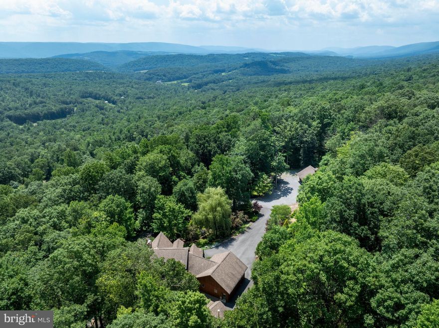 ABSOLUTELY STUNNING is how you will  describe this property. Suitable for permanent residence, family or corporate retreat, hunting lodge or expand on the 113 acres(recently surveyed) for a campground, venue, etc. The options are endless.  5,000 sf of finished space in this custom log home that contains 5 bedrooms and 4.5 baths (3 bedrooms with en-suites, 1 on 1st floor). Upon arrival you will be greeted by the attractive gated entry at Jacks Mountain Rd. Then you will drive up the shaded driveway and  first see the 32' x 48' detached garage with walk up storage/future living space above. It has oil forced air and wood stove heat, plus hot and cold water.  Then you will approach the residence that has an oversized 2 car attached garage. The first floor of the home has a large entry foyer, mudroom, half-bath/laundry room, open floorplan kitchen/dining/living room and a primary bedroom w/bath. 2 stone, wood burning fireplaces add charm and ambiance, 1 in living room and 1 in bedroom.  The primary bath has a jetted tub and separate shower stall.  The 2 story ceiling  in the living room  is filled with light from a multitude of windows. The kitchen has stainless steel appliances and includes a trash compactor. Counters are granite and the peninsula/bar area has  19' of thick, live edge counters. It even includes a kegerator.  The second floor has a middle loft overlooking the living room  and a bedroom to each side with  private baths. There is a secondary loft off 1 bedroom, great for storage,  nursery, etc.  The daylight basement level has recently been finished to include a massive rec room, 2 bedrooms, full bath and a utility room. The exterior expands your living area with many additional spaces. The upgraded wrap around deck  spans 3 sides of the home, with the rear area being covered. Take a few steps down and you are on the massive paver patio that provides a level play area or outdoor dining for a crowd. Adjacent to that is a large river stone firepit area for those cool evenings and chats with friends and family around a crackling campfire. There are numerous trails throughout the property to ride your ATV, mountain bike or hike on foot. The mechanicals have been updated and will definitely impress you. The main heat source is oil hot water, with radiant floor heat in the basement and first floor, with radiators added in key areas and  baseboard on the second floor. The oil is backed up with an external wood fired boiler, that is contained in and enclosed outbuilding that keeps your firewood dry and makes loading the boiler an easy task. The AC system was upgraded to a 5-ton Trane Heat Pump, that keeps you cool in the summer and takes off the chill in the spring and fall. Hot water is provided by 2 Navien tankless propane water heaters.  Everyone knows that winters can bring snow and ice, which sometimes means power outages. Not to worry, the owners had a propane fired Generac 36 KW generator installed. It will power the entire residence to give you peace of mind. The property will come  partially furnished with an option to purchase the air compressor and workbenches in the detached garage.  Located near hunting and fishing opportunities, 10 minutes to Belleville, 50 mintutes to State College/Penn State, 80 minutes to Harrisburg  and 50 minutes to Lake Raystown. There are many local shops, markets, orchards, etc. to discover as you enjoy the laid back lifestyle the area affords.