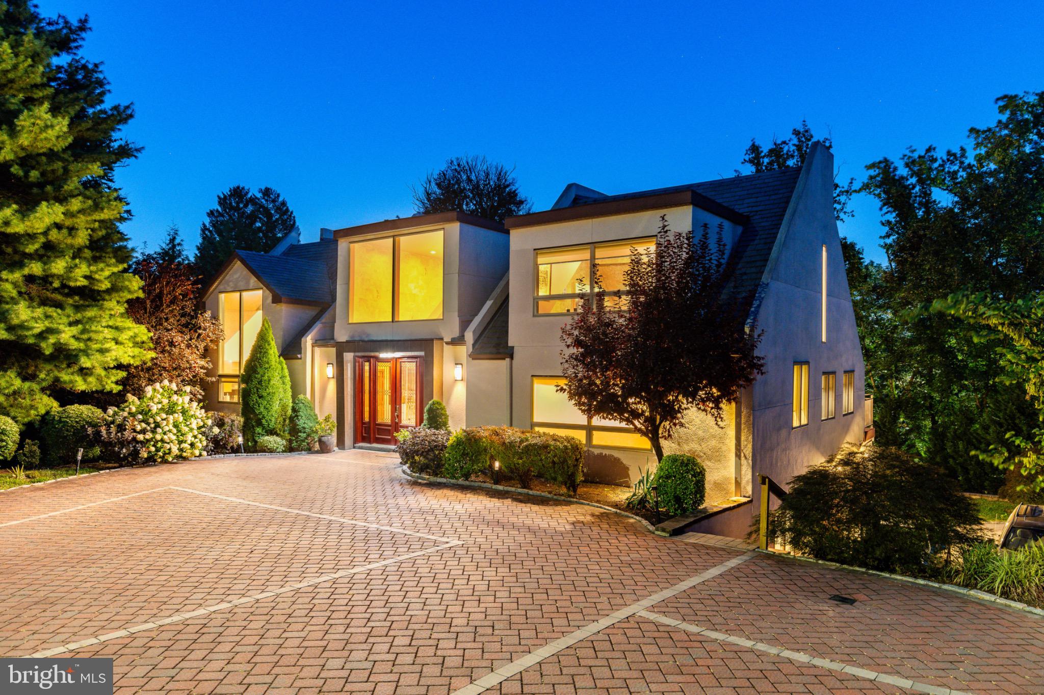 Tucked away within one of the Main Line’s most beautiful neighborhoods, this architecturally significant contemporary , originally inspired by acclaimed architect Hugh Newell Jacobsen , stands out as a unique rare modern gem among Gladwyne’s traditional estates. Known locally as the former “Glass and Cedar House,” the residence retains its striking form while benefiting from contemporary updates. As you arrive, the detailed brick driveway, manicured landscaping, and distinctive design immediately set the tone for this exceptional home.
Inside, soaring 20-foot ceilings, walls of expansive windows, and multiple sliders bathe the interiors in natural light and create a seamless connection to the surrounding greenery. The restaurant-style kitchen is a chef’s dream, appointed with Wolf and Sub-Zero appliances, gas cooking, a wine refrigerator, trash compactor, built-in espresso and coffee maker, a stunning 19-foot quartz island, and Caesarstone countertops - perfect for cooking, entertaining, and gathering. The welcoming first-floor entry features a stunning view with high ceilings and sky lights and is flanked by a large closet and a perfectly placed powder room.
The 3-bedroom, 3.5-bath layout offers both versatility and modern comfort. The spacious first-floor primary suite features a private balcony overlooking the grounds, two generous closets, and an inspiring loft area ideal for a home office, gym, or nursery. The spa-like bath is complete with a soaking tub, radiant heated floors, a high-end Japanese toilet, and an oversized glass shower. A striking floating staircase leads to the lower level, where you’ll find two additional bedrooms with hardwood floors, two updated full bathrooms, a dedicated laundry and utility room, and a sunken family room with access to the back patio. Every window frames tranquil, tree-filled views, enhancing the home’s retreat-like atmosphere.
Additional highlights include a gas fireplace, built-in speakers throughout, dark-stained hardwood floors, landscaped front grounds with Coventry walls, EP Henry stonework slate steps and a deck that runs the entire length of the back of the house overlooking the this beautifully landscaped property . Just minutes from the Schuylkill River, top-rated Lower Merion schools, Philadelphia Country Club, and major highways to Center City and King of Prussia, this one-of-a-kind property offers architectural pedigree, privacy, and a move-in-ready modern lifestyle.