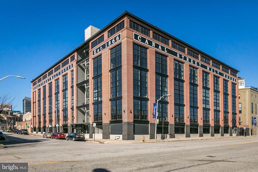Live large in this spacious light-filled industrial loft boasting 2,628 sq. ft. of premier living space. Exposed ducts, columns, concrete, steel, and wood are uniquely blended to create an impressive industrial design. This sophisticated residence has been custom designed using the highest quality materials and finishes.  The home features  on the main level an inviting entry with a large closet, a dramatic great room with 18' soaring concrete ceilings, window walls of glass, striking built-in custom entertainment center/ wall unit, exceptional gourmet kitchen with sleek 42' cabinets, deluxe commercial stainless steel appliances, expansive island/breakfast bar, upgraded granite countertops, a laundry/utility room with washer and dryer. Additional property features include: deluxe hardwood floors, upgraded lighting throughout, dramatic super-sized metal ceiling fan, motorized shades with remotes, and a neutral paint pallet throughout. The impressive wood and steel staircase enhances the main level open floor design. The second level mezzanine loft includes a spacious private en-suite master bedroom with sumptuous bathroom, large walk-in closet with custom closet wood organizers, and access to an expansive private covered balcony overlooking a beautiful common area courtyard. The sumptuous bath has a soaking tub, separate shower, custom vanity, heated flooring, and a linen closet. Two assigned garage parking spaces convey.  An additional storage area is located on the building lower level common area.  The home is heated with natural gas and cooled by central air conditioning. The Canal Street Malt House structure was renovated to create unique space.  The careful design and addition of a large, new building seamlessly blends the historic with the contemporary.  An authentic warehouse-styled exterior contributes to the neighborhood's architecture and cleverly hides a private parking garage for the residents.  The two structures enclose a large, tranquil courtyard with lavish greenery and seating where guests can relax or entertain. The complex is ideally nestled among Baltimore\'s most vibrant neighborhoods.  With the Inner Harbor, Harbor East and Little Italy district literally steps away, there is never a loss for entertainment, nightlife and family fun.  The proximity to award-winning restaurants, Italian bakeries and the Whole Foods Market further enhances urban lifestyle benefits.  The accessibility of I-83 and I-95 ensures swift travel, while the metro stop three blocks away provides direct access to Johns Hopkins Medical Center and the University of Maryland Medical Campus.  The Circulator bus, with a pick-up and drop-off stop within close proximity, makes travel around town effortless. Major street enhancements and business/residential development along the Central Avenue corridor and Harbor East have and will continue to add to the superb community.  Enjoy City living at its best!