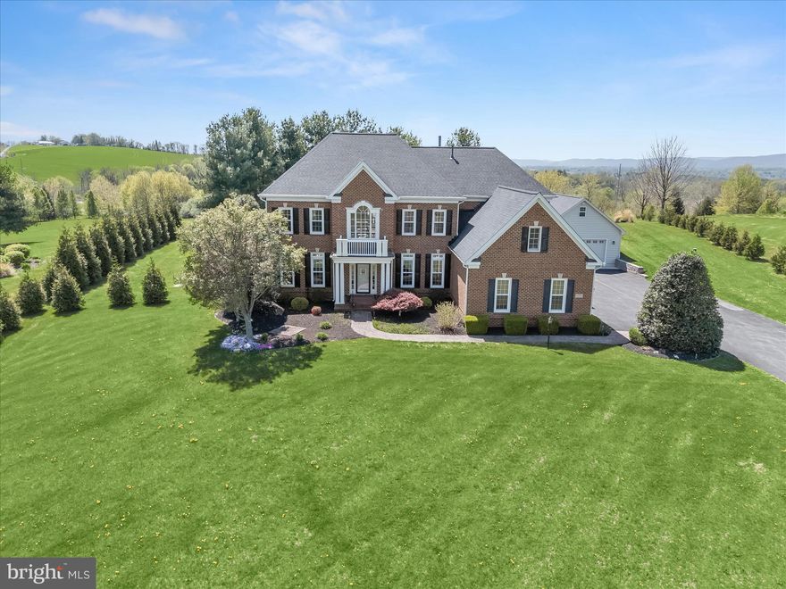 Welcome to 4209 Maryland Court, a stunning retreat nestled in the hills of the Middletown Valley, offering breathtaking views of Maryland National Golf Course and the Catoctin Mountains. Set on a beautifully landscaped 3.15-acre lot, this exceptional residence blends timeless elegance with thoughtful modern upgrades, creating a serene and private setting. Inside, architectural details shine in every room, from gleaming hardwood floors and stately columns to classic moldings and sun-drenched interiors. A grand two-story foyer welcomes you with formal living and dining rooms on either side, setting the tone for the home’s refined design.
The heart of the home is the thoughtfully designed chefs eat-in kitchen, featuring a suite of premium appliances including a Monogram cooktop with range hood and a recently installed Thermador built-in refrigerator, along with granite countertops, a center island with breakfast bar, a planning station, and a walk-in pantry. A complete water filtration system, including a reverse osmosis drinking water system, adds both convenience and peace of mind. The adjoining morning room is filled with natural light from a wall of windows and provides access to the spectacular outdoor living space, complete with a custom patio, hot tub, and outdoor shower station perfect for entertaining or relaxing. The spacious family room is anchored by a cozy fireplace and built-in shelving, while a private office with French doors and a bay window offers the ideal work-from-home space. A mudroom, two powder rooms, and access to the attached garage complete the main level.
Upstairs, the luxurious primary suite serves as a private retreat, featuring a tray ceiling, expansive sitting room with fireplace, two walk-in closets, and a spa-like bath with separate  vanities, soaking tub, water closet, and glass enclosed shower. Three additional bedrooms provide ample accommodations, including one with an en-suite bath and two connected by a Jack-and-Jill bath, along with a convenient upper-level laundry room.
The finished lower level expands the living space with an expansive game room, a media room with wet bar, granite countertops, and wine fridge, an exercise room, a bonus room, and abundant storage.
Additional highlights include Wi-Fi enabled motorized fabric blinds throughout entire first floor and primary bedroom, a three-zone HVAC system for enhanced comfort and efficiency, built-in whole-house surge suppression, an attached oversized three-car garage, and a detached two-story garage equipped with heating and air via mini-splits. The detached garage also features its own 100-amp electrical service, offering excellent flexibility for a workshop, studio, or hobby space, along with an upper-level bonus area ideal for an office or creative retreat. With an extensive list of updates and an unparalleled setting, this remarkable home offers the perfect balance of luxury, comfort, and scenic beauty.
