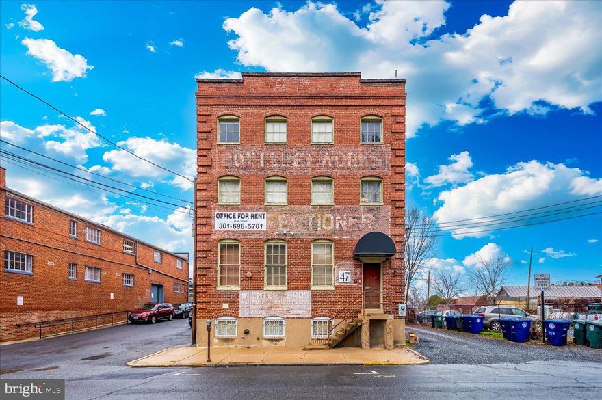 Located in the heart of historic downtown Frederick, this exceptional three-story building sits directly on Carroll Creek, offering a prime location with high visibility and accessibility. The property spans over 10,000 square feet of office space, excluding the basement, and is zoned for commercial/residential use (buyer to verify zoning details). Its strategic placement on Carroll Creek positions it within close proximity to Frederick’s shops, restaurants, and cultural attractions, making it an ideal investment opportunity. Originally constructed in the early 1900s, this building retains its historic character, having previously served as a confectionary factory. Architectural highlights include original heartpine flooring, exposed brick walls, and a three-story open atrium. The property also features an historic elevator, contributing both functionality and a nod to its industrial heritage. A penthouse suite is located on the top level, providing access to an expansive rooftop deck with nearly 360-degree views of the Frederick skyline, including the city’s iconic steeples and Carroll Creek. This feature, along with the open floor plan and industrial design elements, makes the building suitable for a wide range of uses, including office, creative workspace, or mixed-use development. The property is fully accessible, with ADA access available both internally and externally. Additional features include a modern warehouse aesthetic, large windows that provide ample natural light, and the flexibility to adapt to various business or residential needs. This building offers a rare combination of historic charm, modern functionality, and prime location, making it an exceptional opportunity for investors or end users.