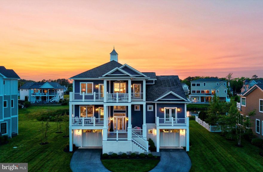 This beautifully designed residence captures the essence of coastal living with its striking nautical blue exterior, clean architectural lines, and expansive porches that invite you to relax and take in the surroundings. Inside, a soothing coastal palette flows throughout the home, with deep blue accents providing a bold contrast to the crisp white cabinetry and sandy-toned luxury vinyl plank flooring. The main level showcases a desirable open-concept layout, thoughtfully designed for effortless entertaining and comfortable everyday living. At the heart of the home, the gourmet kitchen impresses with a sprawling quartz island, gas cooktop, wall oven, and abundant cabinetry. It seamlessly opens to the spacious dining area—complete with a built-in wet bar and wine fridge—and the inviting living room, where a gas fireplace is flanked by custom built-in cabinetry. Both the dining and living areas connect to a generous screened porch with peaceful pond views—perfect for morning coffee or sunset cocktails. This level is also home a private and serene primary suite, ideally positioned to capture views of Rehoboth Bay from both its windows and a private balcony. The spa-inspired ensuite bath features dual vanities, a tiled walk-in shower, a freestanding soaking tub, and a large walk-in closet too. This level includes a spacious laundry room and a flex space currently being utilized as a private office. Upstairs, a versatile loft with wet bar provides additional living space, along with three guest bedrooms and two full bathrooms. From the second-floor porch, enjoy bay views and even a glimpse of the iconic Indian River Inlet Bridge in the distance. The ground level offers garage space for three vehicles along with ample room for beach gear, bikes, and recreational equipment. An elevator services all three levels, providing ultimate convenience. Out back, unwind in your Adirondack chairs while overlooking the tranquil pond and soaking in the sounds of nature. This is a rare opportunity to own a thoughtfully designed home in one of Rehoboth’s most sought-after communities—offering luxury, comfort, and a true sense of coastal serenity.