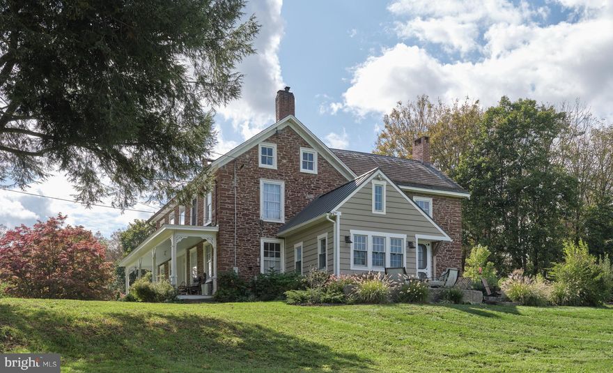 Covered Bridge Farm -- Sitting back from the road in all its vintage splendor, this stone house with a sweeping front porch is exceptional with original architectural features, modern conveniences, and a stunning first floor addition. Ideal as a full-time residence or a get-away second home, it overlooks the Erwinna Covered Bridge, one of the few remaining examples of this type. From the front door, step into the foyer and notice the original curved banister on the staircase. To the left is the parlor (living room) with a wood burning fireplace with Mercer tiles. A bathroom with shower was built beneath the staircase, and the other large room is now used as a great room. Once a dining room (always the largest room in the 1800s) casual or formal dining can be incorporated into this multi-purpose space. The kitchen was upgraded in 2022 with Silestone countertops and recessed lighting.  The heart of this home has a Viking range and is large enough for a table and chairs or perhaps an island for food prep, serving, eating. The focal point is the walk-in fireplace with raised panel wood doors that close and a side door from the driveway opens into the kitchen for convenience. Completing the first floor is the 2019 stunning addition that adds another dimension to this beautiful home. Vaulted ceiling with beams, a stone wall that was once the exterior, large windows, and a door out to a patio overlooking the bridge. Upstairs are two generous sized bedrooms each with an updated bathroom.  A staircase in the kitchen goes up to a laundry area and the main bedroom suite. This home has incredible flexibility on how each room can be used to suit your lifestyle and needs. Rooms are spacious, floors are painted pumpkin pine, there is original hardware in some areas, large deep sill windows provide natural light and views of changing seasons. The exterior is wonderful for relaxing and entertaining. There is a 3-sided shed, an enclosed pasture in which sheep and chickens roam, two bluestone patios, walkways and many new trees and beautiful landscaping were added. The remnants of stone walls enclose a large, open area and await your creative ideas for making this area an unique place. The specialness of this property is the retention of timeless features that provide character and a relaxed ambiance. Rolling lawn areas, a creek, a quiet country road, and history are the distinguished features of this home. Steeped in history and the love of a family that owned it for many generations, it is an exceptional property that provides quiet country living with close proximity to the many exciting surrounding towns and areas that make living in Upper Bucks County a great location. The house, the setting, amenities, and location will delight you.  Welcome home!