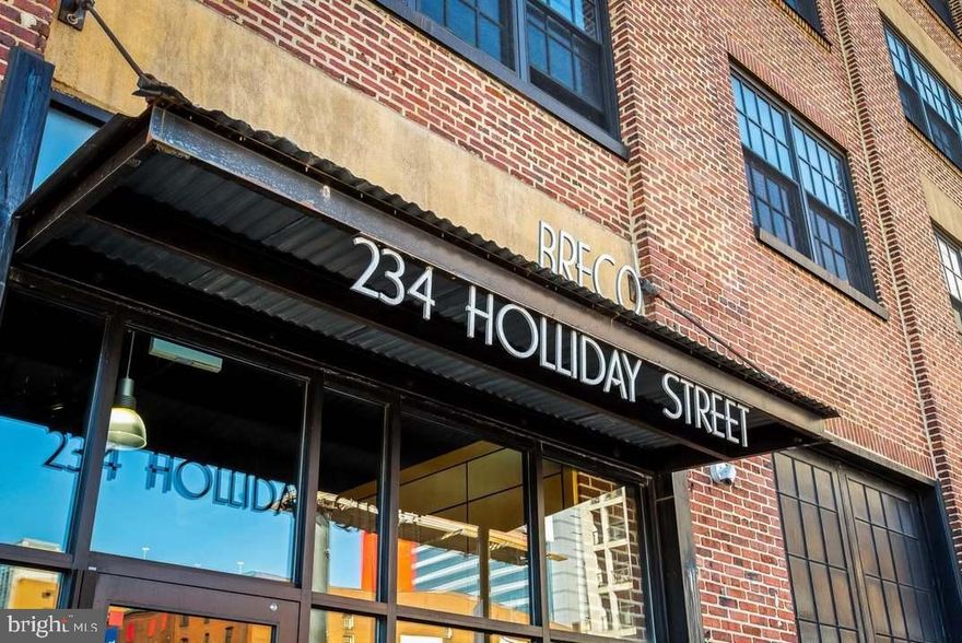 Welcome to 234 Holliday Street, located in the desirable Breco Condominium in the heart of Baltimore City. This contemporary 1 bedroom, 1 bath urban loft-style condo offers modern living with a unique industrial charm. Featuring high ceilings and a spacious open layout, it is the perfect balance of comfort, character, and convenience.  The Breco is a converted century-old printing press building that has been converted into 32 unique and stylish condominiums. The industrial feeling of the building has been preserved while developing a sophisticated open concept living space.   The moment you step inside, you are greeted by the warm glow of refinished maple floors and the stunning industrial aesthetics that define this loft. Exposed brick walls and ductwork add to the character, while the 12-foot ceilings create a sense of space and light. The open floor plan is ideal for entertaining or simply enjoying the spaciousness of your home.  With a complete wall of windows to allow for maximum light, the dramatic aesthetic of the living and dining areas creates a welcoming and airy environment.    The open kitchen boasts granite countertops, plenty of storage, and modern finishes that make cooking and meal prep a delight.  Shoji doors to the bedroom add a stylish touch while maintaining privacy, and the sleek finishes throughout are complemented by the rustic charm of the loft’s exposed elements.    The bedroom offers ample space for your furniture and storage, again with plenty of natural light pouring in through large windows. The updated bathroom is conveniently located just steps away, featuring a clean, modern design.    **    Located one block from City Hall, plus just minutes from Lexington Market, Little Italy, Harbor East, and the Inner Harbor. Enjoy easy access to all major commuter routes including I-83 and public transit options, and hop directly across the street to spend your Sunday mornings perusing the Baltimore Farmer's Market from April through December. CFG Arena, Camden Yards and M&T Bank Stadium plus loads of great restaurants, shops and entertainment are all within a mile or two and University of Maryland, Johns Hopkins and Mercy Medical Center are oh-so-convenient.