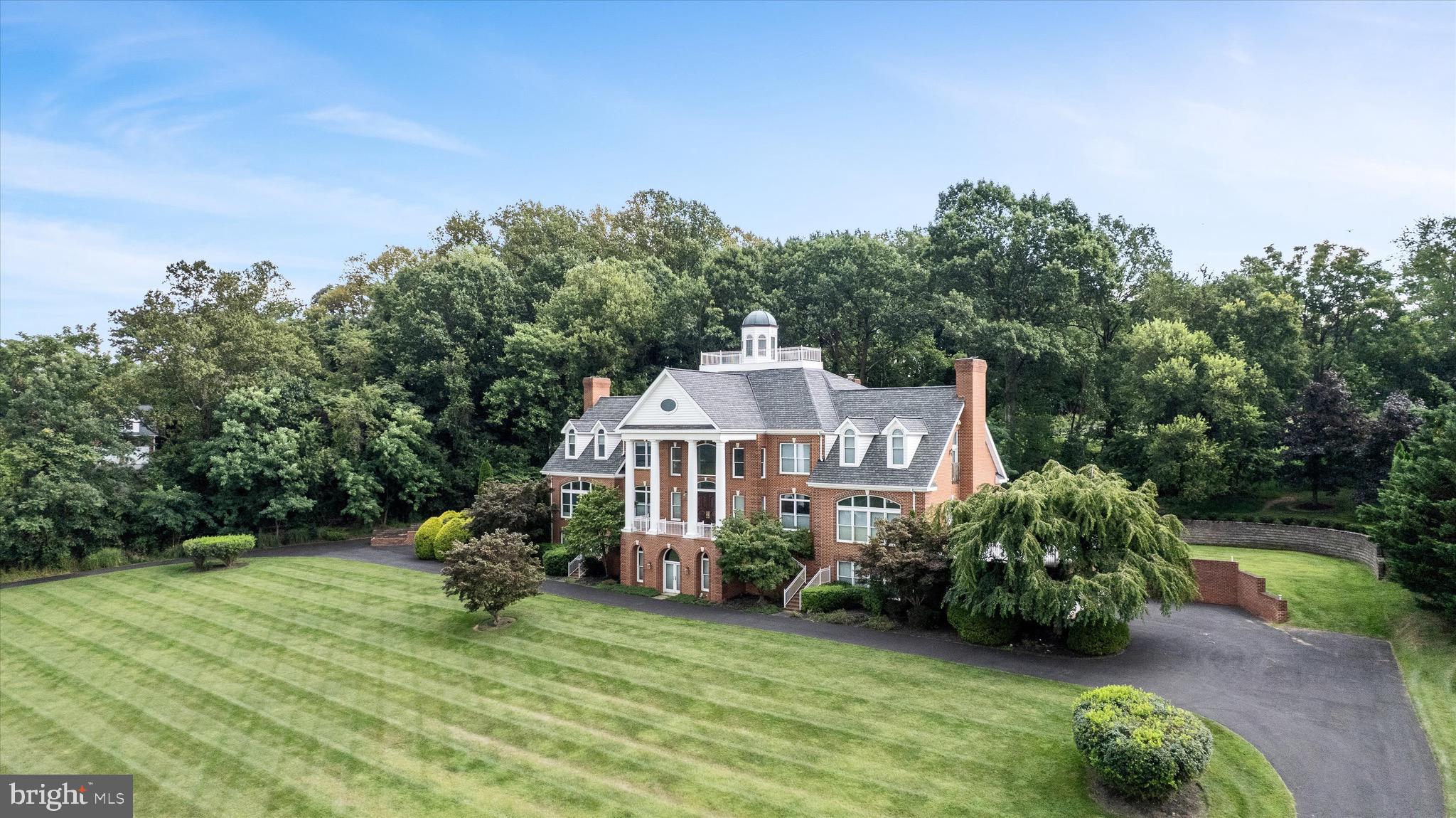Welcome to 18037 Clendenning Circle, an iconic residence nestled in the prestigious Stoneleigh community of Round Hill, VA, offering unparalleled panoramic and mountain views. This exquisite builder’s personal residence stands as a testament to thoughtful design and craftsmanship. With a commanding presence at over 50 feet high, it boasts a widow’s walk on the fourth level, making it the highest point of any home nearby.
Spanning an impressive 8,096 square feet above grade, this grand home is perfect for both entertaining and family comfort, with the potential to expand to over 12,000 square feet upon customizing the ready-to-finish lower level. The main-level bedroom with soaring 12 and 14 foot ceilings and expansive dual walk-in closets, Additional four bedrooms with four en suite baths upstairs which includes a second primary bedroom.
Step inside to discover custom solid wood doors and majestic mahogany French front doors, complemented by grand moldings throughout. The gourmet kitchen, equipped with Sub Zero appliances and dual dishwashers, seamlessly opens to the breakfast and family rooms. Enjoy the elegance of formal living and dining rooms that flank a two-story foyer with grand curved stairs.
The residence is adorned with refined details such as beefy crown and decorative moldings, built-ins, columns, hardwood and marble floors, high ceilings. Dual patios for entertaining or quiet evenings. five-car garage, circular drive. Just 35 minutes to Dulles Airport, one hour to DC.