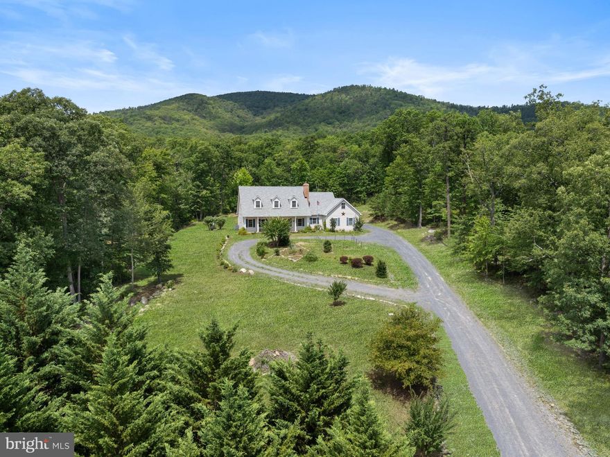 Are you looking for the perfect mountain retreat? Then look no further! This stunning 4 bedroom, 4.5 bath cape cod is situated on over 4 acres of pristine land! Located minutes to George Washington National Forest- and your lot line borders the Park. Plenty of land to explore and enjoy! Located in a serene and secluded area, this home offers breathtaking views of the surrounding mountains and forests.  
The main entrance greets you with a stunning front porch-perfect to soak in the amazing views. Walk into the spacious family room with Hardwood flooring and stone surround fireplace with wood stove insert. The fully equipped kitchen features eat in area, center island, stainless appliances with a gas range.  Formal dining room to sun room with a walk out to the screened in porch. Large laundry room with built in cabinets and counters. Main level primary with hardwood flooring and handicap accessible primary bath. Roll in shower with ceramic tile surround, double vanities, soaking jetted tub and 2 walk in closets. 
The other side of the main level features 2 additional bedrooms with a jack and jill bathroom.  Upper level features a large gathering room and bonus room and additional bedroom with a full bath.  Attached 2 car garage with carport area to an additional 2 car garage. The expansive land offers endless possibilities for outdoor activities such as hiking, playing, and wildlife watching! Relax on the screen in porch, patios and soak in the peaceful atmosphere. Updates include brand new roof, leaf gutter guards, fresh paint throughout, all new fire alarms, newer well pump and pressure tank. Home also includes a whole house generator. Propane tank leased through Holtzman and was recently filled which will convey to buyer. 
Don't miss this opportunity to own your piece of paradise today!