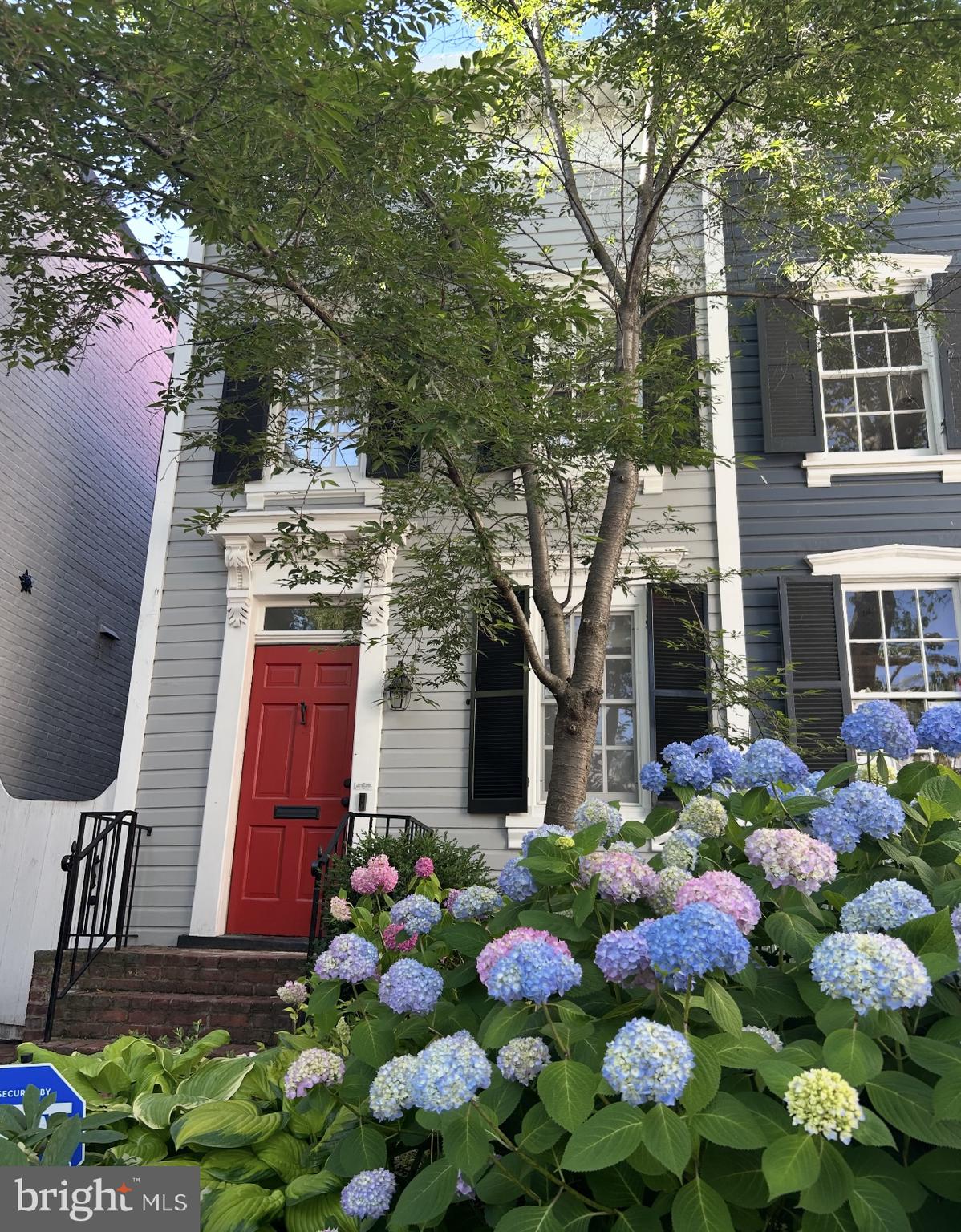 Charming Historic Federal on Coveted Cobblestoned O Street
Nestled on one of Georgetown’s most picturesque blocks, this semi-detached Federal-style residence offers timeless elegance and rare privacy thanks to its deep setback and elevated position. Built in 1840, the home retains rich original details—wide-plank hardwood floors, a period mantel framing the wood-burning fireplace, and generous windows that bathe the home in natural light.
The main level is designed for both refined living and effortless entertaining, featuring a sophisticated living room with original fireplace and a formal dining room ideal for hosting intimate Georgetown dinner parties. An updated kitchen with stainless steel appliances opens to a beautifully landscaped, multi-tiered brick patio—an inviting space for al fresco gatherings. A powder room and laundry room on this level add everyday convenience to the home’s historic charm.
Upstairs, two well-proportioned bedrooms share a full bath, while the lower level offers excellent storage space. Located just steps from Wisconsin Avenue, vibrant M Street, charming parks, and Georgetown’s finest shops and restaurants, this is a rare opportunity to own a piece of D.C. history in one of its most desirable neighborhoods.