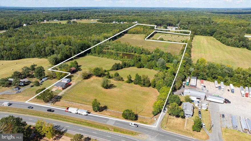 A truly rare 31.1-acre land offering in Stafford County comprised of four separate parcels, creating exceptional flexibility for a private estate, working farm, family compound, or potential future division. With dual road frontage on both Warrenton Road (Route 17) and Truslow Road, this property offers visibility, access, and long-term opportunity that is increasingly difficult to find. The rolling landscape features approximately 18 acres of cleared and previously hayed fields, extensive open pasture, and fencing already in place, making it ideal for horses, livestock, or agricultural use. This was long ago a beautiful, working horse farm. A picturesque one-acre pond (great fishing here!) anchors the property, complemented by abundant wildlife and mature natural buffers. Existing infrastructure includes multiple barns (four-stall and two-stall configurations with paddock), as well as a 30x25 metal building suitable for equipment storage, workshop, or garage use. With four parcels included, the layout lends itself to multi-generational living, future homesites, or builder exploration (subject to county approvals). The property is improved by a three-bedroom, 1.5-bath brick residence set off the road, with nice square footage and updated main-level finishes. Ideally positioned just minutes from Hartwood, Route 17 conveniences, I-95, and Downtown Fredericksburg, this offering combines scale, infrastructure, dual-road frontage, and location, a powerful combination rarely available in today’s market. A true land opportunity with immediate usability and long-term upside.