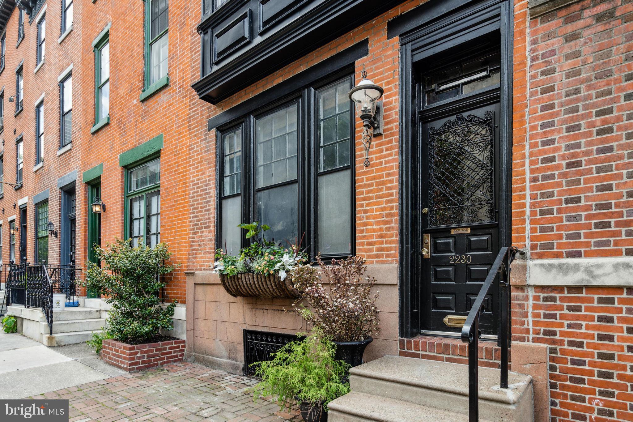 This stunning and recently updated townhome, located between Rittenhouse Square and Fitler Square, features high-quality upgrades, custom and original details, two outdoor spaces and coveted off-street parking. Enter the classic brick- front façade through the original wooden door featuring an arched glass window and intricate metalwork. Once inside notice the whimsical vestibule wallpaper, slate gray tile flooring and the 15-panel glass interior door. The expansive living room features 10 ft high ceilings, hardwood flooring with inlaid border, abundant recessed lighting, and oversized north facing windows. The gorgeous wood floors continue to the formal dining room which features an antique wooden door with functioning leaded glass windows, wood side panels as well as a leaded glass mini skylight above. A pointed archway connects to the recently renovated and tastefully designed gourmet kitchen with a mixture of natural wood, navy and beige shaker-style cabinets complete with stone countertops, subway tile backsplash and under cabinet lighting. The stainless-steel appliances include a Thermador range with chimney hood & dishwasher, microwave drawer, and counter-depth French door refrigerator. There’s a sweet built-in banquette at the back of the kitchen which offers views to your very own brick-paved patio and separate parking space with electronic gate. This level also features a convenient powder room, tons of pantry/storage space and a coat closet. Follow the custom designed railing to the second floor where you’ll find the luxurious primary suite with a wall of closets, 3 oversized windows and a serene, spa-like bathroom featuring a walk-in marble shower with bench seat, frameless glass doors, rain showerhead and inlaid tile accents. The second bedroom on this level is perfect for a library or den and is complete with a wood burning fireplace and mantle, abundant built-in shelving for the bookworm and provides access to the 2nd outdoor space; a lovely and spacious composite deck for outdoor dining or morning coffee. This level also has a powder room with a laundry area featuring full-size stackable LG washer and dryer as well as additional space for folding and/or storage. The third level of this townhome has two more spacious bedrooms, each with plenty of closet space and fabulous natural sunlight. A den/ small bedroom is also located on this level and works perfectly as a home office. A full walk-in closet is also located off the hallway. The third floor full bathroom shines with gold fixtures, a brand new modern vanity and a shower/tub combination with 2x10 subway tiles in herringbone pattern. The basement is dry for storage and houses all mechanicals including one of the two HVAC systems (second system is on the 3rd floor). This well-maintained and recently updated townhome is in pristine condition and enjoys an ideal Center City location with a walk score of 98. It is conveniently located within walking distance to Rittenhouse Square, Fitler Square, the Schuylkill River Trail, CHOP, UPENN and local favorites include Ambrosia and Rosy’s Taco Bar. Last, but certainly not least, this home is located within (and only three blocks away) from the award-winning Albert M. Greenfield elementary school catchment.