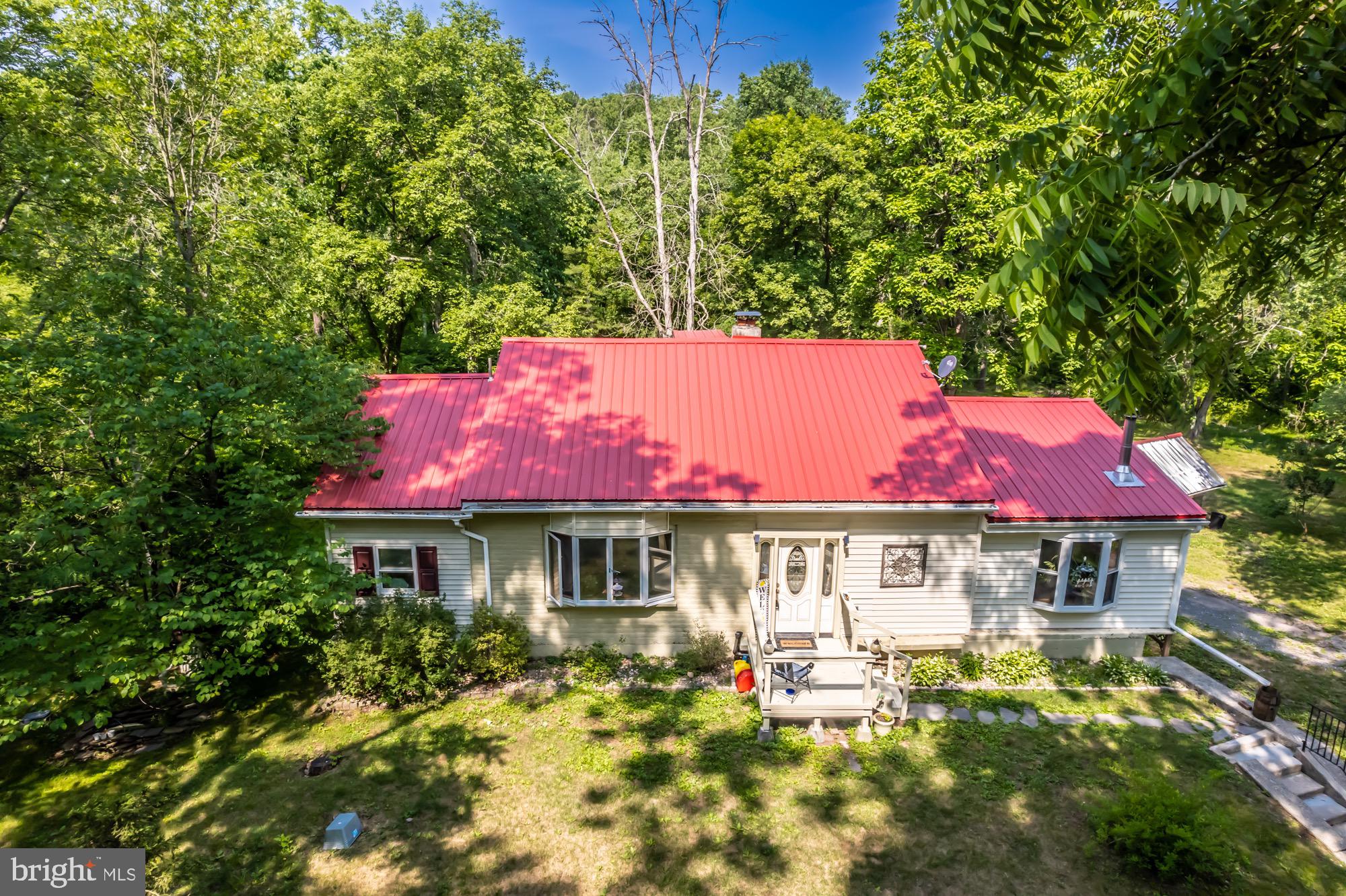 If you’re looking for a tranquil setting in Twin Valley School District …. Here it is!  6.49 acres with two creeks in your back yard in addition to a variety of birds and wildlife. Mostly hardwood throughout the home. The tin roof was installed in 2020 on the home and the outbuildings, also new siding and some new windows. Whole house water filter system. Entering the home through the foyer with a closet and shelves with an inner door as well, into a dining room (presently being used as a sitting room) with an electric fireplace and built ins.  To the right is the large  new kitchen with a country flavor – wood on walls with faux wood flooring, nice sized pantry with built in shelves with a farm type door, two new windows and a large island.  New piping for a wood burning stove is also in place – ready to add the wood burning stove. To the left of the dining room, enter into the living room with another large electric fireplace with built in bookshelves.  The sunroom has sliding glass doors with lots of windows, tall ceiling (needs some personal touches to be complete). Three bedrooms (bedrooms need personal touches as well). Full bath with tile flooring,  Upstairs you will find a very large area which could easily be finished off as two bedrooms or one large room.  The unfinished basement has all of the fixings for another full bath. In place are the working shower and toilet, and the pedestal sink and cabinet with mirror is just waiting to be installed – enclose all three and you have a full bath.  The basement also has a wood burning stove that is capable of heating the entire house.  There is a bilco door leading to the back yard. There are two 1 car garages – one on each side of the home.  One has an inside entrance.  In the back yard you will find a picnic area, fire pit, greenhouse, chicken coop and so much more.  There’s a lot of charm in this one.  Convenient to shopping, restaurants, diners, fast food and gas stations. Come on out and see for yourself ………