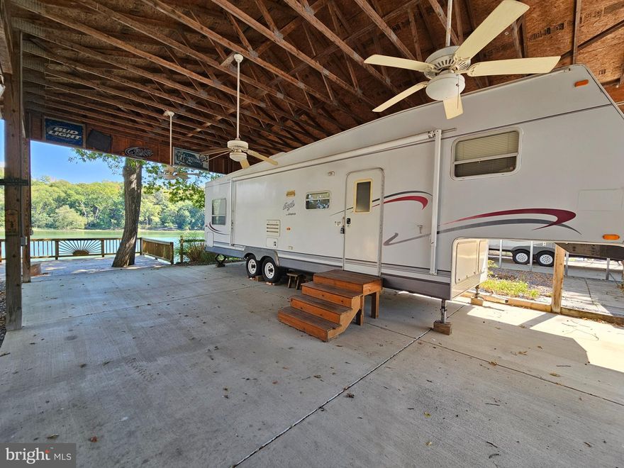 Welcome to Block 1 lot 35 Boo Boo Blvd in Riverbends Rv Campground. Riverbend is 400 Acres of SEASONAL recreational campground full of amenities located on the Potomac River in Falling Waters, Wv. OPEN APRIL 1 - NOVEMBER 1 - This is a fun & entertaining community, yet relaxing. This lot is stunning located right on the Potomac River with direct access including a Pontoon Dock and Catwalk to walk right out to your boat! MUST SELL
This lot features a large concrete pad and surrounded by gravel making it almost Maintenace free! Just come, enjoy, relax and make memories right under the large stick-built Pavilion with lean to covering an outdoor kitchen area, 5th wheel camper that has been kept in great condition, gas Club Cart (4 seater) The Pavilion is fully wired with electric outlets and ceiling fans to keep that fresh air coming off of the river flowing. There is plenty of parking on the gravel driveway space. Everything you see conveys, including the shed. Come spend time on the deck overlooking the river and built on a solid concrete wall and you will feel right at home here. The lot next door is also for sale Block 1 lot 36. These can be purchased together, making it perfect for a group of friends or family to create memories side by side! Call today for your personal tour. Approx. 10 miles of Deep water on the Potomac River access for boating, fishing & swimming. Yearly membership ($1,987) plus a $200 initiation fee for new owners, includes water, Pump outs, electric, trash and the park amenities such as 3 pools, putt putt course, Horseshoe club, Boat club, Poker runs, Trick or Treat, Christmas in July, live bands, basketball court, tennis court, fireworks, car show, Church, restaurant, bar, convenience store (Great food), playground, volleyball, ball field and much much more. Bring your golf carts, water toys and come enjoy life!