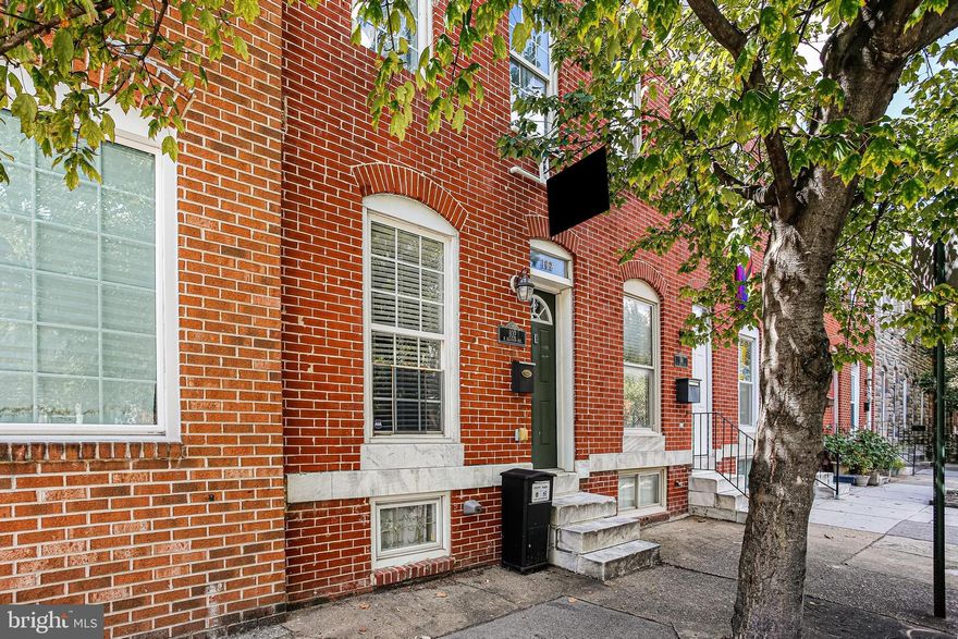 Step into this beautifully updated all-brick Patterson Park rowhome offering 2 bedrooms, 3 full baths, a private parking pad, and just over 1,200 sq ft of living space. Freshly painted and professionally staged, this sun-filled home welcomes you with hardwood floors, tray ceilings with crown molding, recessed lighting, and an exposed brick accent wall that adds warmth and charm to the open-concept main level. The kitchen features granite countertops, stainless steel appliances, a tile backsplash, and a breakfast bar—perfect for entertaining. The upper level includes two spacious bedrooms and two full baths, including a primary suite with access to a private deck. Extensive work has recently been done on the rear upper deck, providing a great space to relax or unwind. The finished basement offers a flexible recreation room, third full bath, and laundry area. Complete with a private parking pad and just blocks from Patterson Park, shops, restaurants, and commuter routes, this home blends style, function, and unbeatable location. Don't miss out on this gem!