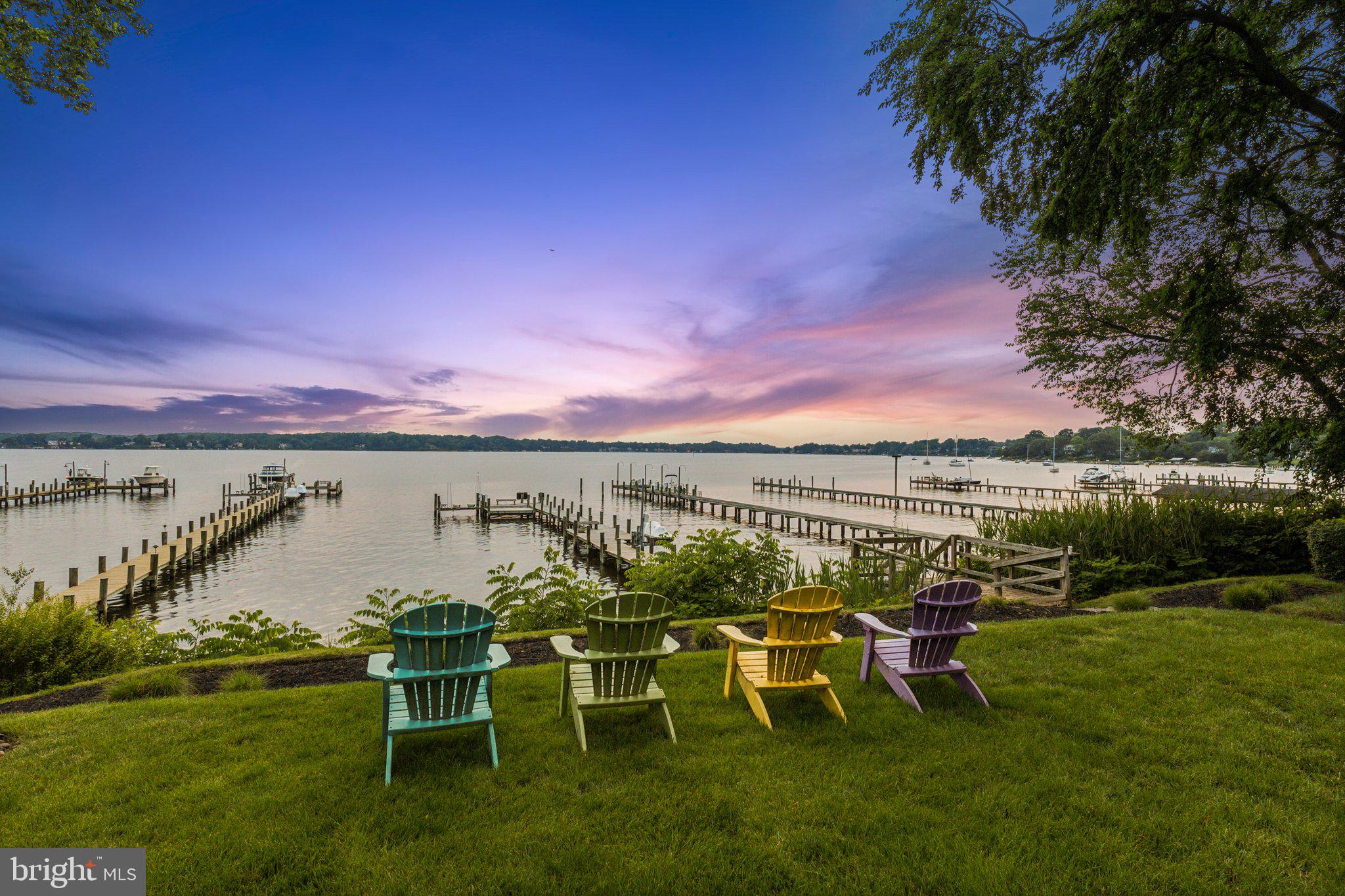 "Sunset on the Severn" — A gated, custom contemporary estate perched on 72 waterfront feet with a private pier, boat & jet ski lifts. A dramatic two-story great room with floating catwalk and wall of glass serves as the heart of this entertainer’s dream.
Just 15 minutes from downtown Annapolis, this Severna Park residence offers refined seclusion with seamless access to the heart of the Chesapeake. Designed to open upward and outward—toward light, toward water—every inch of this home invites you to embrace the surrounding beauty and live in rhythm with it.
The main level blends form and function, anchored by a spacious eat-in kitchen and breakfast bar that flow effortlessly into both formal and informal living areas. A tucked-away family room with custom built-ins creates a cozy retreat, while art niches and clean architectural lines lend a sense of curated calm.
Upstairs, the expansive primary suite features a private balcony with tranquil views, a custom walk-in closet, and a spa-like bath with dual vanities, a jetted tub, and a walk-in shower. A rear staircase leads to two additional bedrooms, a full bathroom, and a dedicated upstairs laundry.
The walkout lower level is built for entertaining, featuring a stunning antique Victorian bar and a generous recreation room with a full bath—ideal for a fourth bedroom, fitness studio, or creative space. Just outside, a stone patio and manicured gardens offer a peaceful escape where birdsong and river breezes create a sense of timeless calm.
Additional highlights include an oversized three-car garage with extensive storage, solar panels for year-round efficiency, a stone-paver motor court, a lily pad pond, and a garden path that gently winds to the private waterfront.
Here, you don’t just live by the water—you live in rhythm with it. Affectionately named Sunset on the Severn for its breathtaking evening views, you will absolutely love being home.