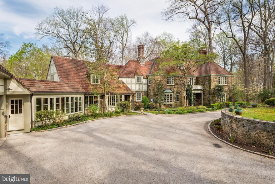 Set on 1.76 acres, this stone Colonial is defined by its elevated setting, architectural proportions, and a level of craftsmanship rarely reproduced today. A courtyard approach introduces the home and reinforces its architectural presence. The exterior reflects the character of the Main Line’s most established homes, with stone construction, detailed trim work, and arched openings.

The home is set within a mature, tree-lined landscape with views from nearly every room. It remains just minutes from Suburban Square, Ardmore, and the Main Line’s primary amenities.

A center hall entry introduces the original portion of the home, where a paneled library, formal living room with fireplace, and dining room retain their architectural integrity with detailed millwork, beamed ceilings, and random-width hardwood floors. French doors connect the main living spaces to several flagstone terraces, extending the living areas to the outdoors.

The home transitions into a fully reimagined kitchen, dining, and family room, designed as the home’s central gathering space. A vaulted ceiling, expansive windows, and direct access to the grounds bring in natural light throughout the day. The kitchen is equipped with high-end appliances, a large island with seating, and adjacent informal dining, all flowing seamlessly into the family room.

Supporting spaces include a butler’s pantry, mudroom with secondary entrance, and a sunlit gallery connecting to the three-car garage.

A privately positioned upper-level suite above the garage, accessed by a separate staircase, offers flexible use as a home office or additional bedroom with full bath, well suited for guests, work, or separation from the main living areas.

The primary suite is located within the main bedroom level, offering windows on three sides, two walk-in closets, and a renovated bath with heated floors. Each additional bedroom is en suite, providing comfort and flexibility for both everyday living and hosting.

The outdoor setting includes terraces overlooking the pool and surrounding landscape, creating distinct areas for dining, entertaining, and quiet use.

Improvements include a three-car garage with finished space above, updated kitchen and family room, guest suite on the main level, multiple HVAC replacements, rebuilt chimneys, refinished floors, and enhanced landscaping.

This is a property that combines architectural character with modern livability in a setting that feels established, yet remains closely connected to everything.