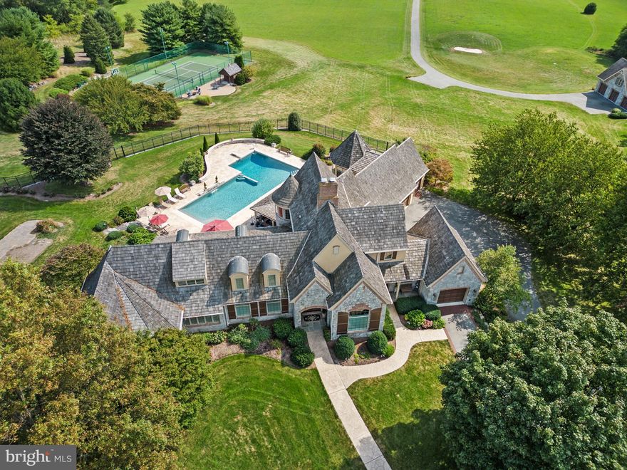 Located in the private community of Lauxmont Farms is this magnificent estate boasting a main residence, in-ground pool, two-story carriage house, tennis/pickle ball court, and picnic pavilion, all sitting on a peaceful and private 18-acre lot. Stunning views of the Susquehanna River add to the distinctive features of this property. Gorgeous inside and out, the exterior of the custom home is accented by stone and turrets. The pool area off the main house is spectacular and adorned with travertine tile. Surrounding the pool is a built-in grill island, comfortable seating area with fire pit, cabana, kitchen, and a separate room with pool lockers and storage. On the main level of the home, cooks will love the chef's kitchen featuring a dining area, dual-level island with seating, wet bar, breakfast room with fireplace, and there’s even a dumb waiter to the lower garage entry. In a separate portion of the house off the kitchen is a unique art room and office where you’ll enjoy more stunning views. This space also houses a large walk-in storage pantry. Located on the main floor is the primary bedroom and private bath along with a formal dining room, living room, second office, and exercise room. The second level of the home hosts two bedrooms and two full baths. The finished lower level includes a fully equipped kitchen, bedroom/game room, full bath, living room, and separate laundry, making the space perfect for everyday living or for family and guests staying over. In the unfinished part of the lower level, you’ll find a cedar closet, workshop, and plenty of extra storage space. The home comes complete with an attached three-car garage and a separate single-car garage opening to the laundry room and mud room. The tennis/pickle ball court also provides a basketball court, option for a volleyball court, equipment storage building, and patio with a fire pit. The carriage house offers additional parking for three cars, a bathroom, and an office on the second level with piping installed to add a kitchen if desired. A private driveway in back of the home leads to the carriage house. Next to the carriage house is a picnic pavilion hosting a grill, hot and cold water sink, fire pit, and an adjacent bathroom in a stone outbuilding. It’s a perfect spot for outdoor gatherings. On the back part of the property, there are 15 flat acres ideal for horses, and water lines exist if needed. The grounds also include one golf hole with a sand trap, a multi-station irrigation system, as well as a diesel generator in another stone outbuilding that automatically starts whenever there is interruption of power. This area also can be designed as a fueling station for diesel cars. Don’t miss the chance to see this incomparable estate for yourself!