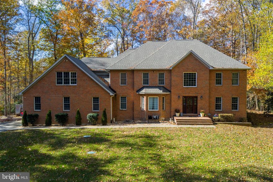 Potential VA-assumable loan, This five-bedroom, six-bathroom brick home, privately positioned on a wooded lot just under four acres. A long, tree-lined driveway creates an estate-like approach and a true sense of separation, while still offering quick access to shopping, dining, commuter routes, and highly regarded schools and no HOA.

The home offers nearly 5,000 finished square feet with hardwood floors throughout the main and upper levels. A two-story foyer opens to formal living and dining rooms, both generously sized and well suited for entertaining. The dining room features tray ceiling detailing, crown molding, and ample space for larger gatherings and holiday meals.

The kitchen, updated in 2020, remains bright and functional with white cabinetry, marble countertops and backsplash, stainless steel appliances including a gas range, four ovens, pantry storage, an island with seating, and adjacent table space that accommodates both daily living and entertaining.

Just off the kitchen, the family room serves as a welcoming central space with an impressive all-brick wood-burning fireplace, fully rebuilt in 2022, creating a warm and inviting focal point. Sliding doors lead to a two-story rear deck with a built-in hot tub overlooking the private, wooded backyard.

The main level includes a powder room and a full bathroom designed for accessibility, featuring a roll-in shower.

Upstairs, the primary suite offers a true retreat with hardwood floors, tray ceiling, sitting area, and its own wood-burning fireplace, also rebuilt in 2022. A private door leads to the upper-level deck, providing a quiet outdoor space to enjoy the surrounding natural setting. The en suite bathroom includes a jetted soaking tub, tiled shower, dual vanities with granite countertops, and a spacious walk-in closet.

Bedrooms two and three share a Jack-and-Jill bathroom with double vanity and tub/shower combination. The fourth bedroom includes its own updated bathroom with a frameless glass shower, white cabinetry, and marble countertop. The fifth bedroom also features hardwood flooring and access to a full bathroom with a tub/shower combination.

The lower level is unfinished with a bathroom rough-in, offering flexibility for future living space, recreation, or storage.

Notable updates and features include a new roof installed in 2022, all fireplaces rebuilt in 2022, a three-car garage, tankless water heater, and HVAC systems replaced within the past few years.

For those seeking privacy, space, and a home that feels tucked away without being remote, this property offers a rare combination of tranquility, functionality, and everyday convenience.