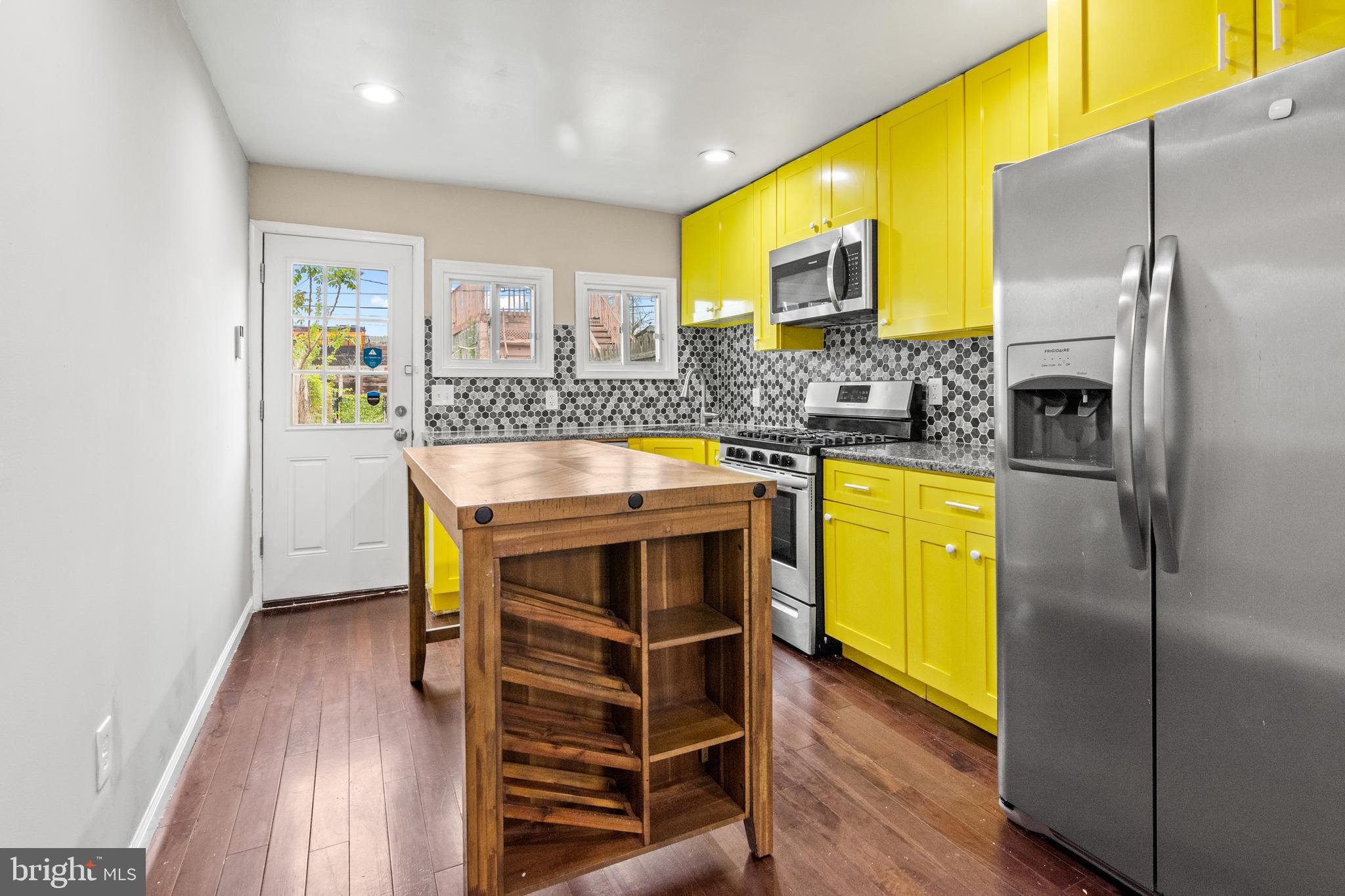 Welcome to 1122 Sargeant Street — a vibrant and move-in-ready row home in the heart of Baltimore’s historic Pigtown/Washington Village neighborhood. This spacious 3-bedroom, 3-full-bath home offers a unique blend of modern updates and classic city character, with thoughtful touches throughout that make it a rare gem in an evolving and exciting community. Step inside to an open-concept main level featuring striking coffered ceilings, a brick accent wall, recessed lighting, and gleaming hardwood floors. The updated kitchen boasts granite countertops, a large wood island, soft-close cabinetry, a deep stainless steel sink with garbage disposal, and a full suite of stainless steel appliances including a gas range, microwave range hood, dishwasher, and large refrigerator—perfect for cooking and gathering. Upstairs, you'll find soft carpet underfoot, a spacious primary suite with a private bath, and a second bedroom that works equally well as a guest space or home office, along with a second full bath in the hallway. The fully finished basement offers a versatile bonus room, a third full bathroom, laundry with front-loading washer and dryer, and ample storage space. One of the home’s most coveted features is the expansive, enclosed two-car parking pad with a locking steel gate and private access door—a rare find in Pigtown. The outdoor space includes low-maintenance turf and a cozy patio area ideal for relaxing, entertaining, or enjoying your own urban garden bed. Recent upgrades include a brand new roof (2023) and iron security bars over front entry points and locking steel gate to parking area. The home is equipped with a SimpliSafe security system and Eufy video doorbell, both of which convey. Located on a tucked-away street just steps from Carroll Park, the B&O Railroad Museum, and a growing lineup of neighborhood favorites like Swill by Blacksmiths, The Stoop Coffee, Culinary Architecture, Nick’s Rotisserie, and Mystique Barrel Brewing. You're just a short walk from M&T Bank Stadium, Camden Yards, and the University of Maryland Medical Center, with easy access to I-95 and the BW Parkway for stress-free commuting. 1122 Sargeant Street offers the perfect combination of comfort, convenience, and city energy. This one truly checks all the boxes. Don't miss your chance to make it yours.