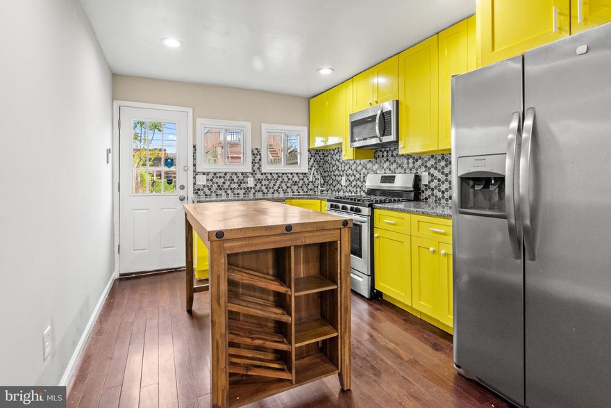 Welcome to 1122 Sargeant Street — a vibrant and move-in-ready row home in the heart of Baltimore’s historic Pigtown/Washington Village neighborhood. This spacious 3-bedroom, 3-full-bath home offers a unique blend of modern updates and classic city character, with thoughtful touches throughout that make it a rare gem in an evolving and exciting community. Step inside to an open-concept main level featuring striking coffered ceilings, a brick accent wall, recessed lighting, and gleaming hardwood floors. The updated kitchen boasts granite countertops, a large wood island, soft-close cabinetry, a deep stainless steel sink with garbage disposal, and a full suite of stainless steel appliances including a gas range, microwave range hood, dishwasher, and large refrigerator—perfect for cooking and gathering. Upstairs, you'll find soft carpet underfoot, a spacious primary suite with a private bath, and a second bedroom that works equally well as a guest space or home office, along with a second full bath in the hallway. The fully finished basement offers a versatile bonus room, a third full bathroom, laundry with front-loading washer and dryer, and ample storage space. One of the home’s most coveted features is the expansive, enclosed two-car parking pad with a locking steel gate and private access door—a rare find in Pigtown. The outdoor space includes low-maintenance turf and a cozy patio area ideal for relaxing, entertaining, or enjoying your own urban garden bed. Recent upgrades include a brand new roof (2023) and iron security bars over front entry points and locking steel gate to parking area. The home is equipped with a SimpliSafe security system and Eufy video doorbell, both of which convey. Located on a tucked-away street just steps from Carroll Park, the B&O Railroad Museum, and a growing lineup of neighborhood favorites like Swill by Blacksmiths, The Stoop Coffee, Culinary Architecture, Nick’s Rotisserie, and Mystique Barrel Brewing. You're just a short walk from M&T Bank Stadium, Camden Yards, and the University of Maryland Medical Center, with easy access to I-95 and the BW Parkway for stress-free commuting. 1122 Sargeant Street offers the perfect combination of comfort, convenience, and city energy. This one truly checks all the boxes. Don't miss your chance to make it yours.