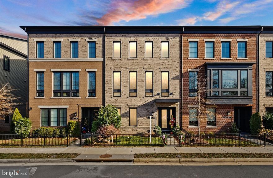 Welcome to this beautifully upgraded Miller & Smith Uptown townhome, a 24-foot wide layout offering nearly 3,300 square feet of thoughtfully designed living space in the center of One Loudoun. With its direct views of the wooded side of Central Park in the front and open green space behind, the setting feels peaceful while still being only steps from everything the community offers.

From the moment you step inside, the home feels generous and inviting. The entry level opens to a spacious room currently used as a theater, complete with a granite-topped snack area and a full en-suite bath. Its size and flexibility make it easy to envision as a guest suite, office, or in-law space. Down the hallway is an additional room that works well as a small bedroom or private office. This level also provides access to the finished two-car garage, which features epoxy flooring and plenty of storage. Throughout the home, you will find upgraded stair railings with modern balusters, and every window is fitted with custom blinds for a clean, cohesive look.

The main living level feels bright and expansive thanks to the 10-foot ceilings and wide-plank engineered wood flooring. The family room is anchored by a striking gas fireplace with a custom tile surround, and the seller added sound-dampening panels that enhance movie nights and quiet evenings alike. A large sliding door leads to the covered terrace, creating an easy flow for indoor-outdoor living.
The kitchen was designed with both everyday function and entertaining in mind. It offers a long quartz island, a professional 6-burner gas cooktop with a range hood, GE Café appliances including double ovens, a French door refrigerator, a dishwasher, and a microwave, as well as upgraded cabinetry and a stylish tile backsplash. A dedicated coffee or beverage area with a built-in drink cooler adds convenience and charm. The dining area is comfortably sized and features Restoration Hardware lighting that elevates the entire space. A powder room completes this level.

Upstairs, the primary suite serves as a quiet retreat. The bedroom includes a ceiling fan and additional sound-reducing panels, and the custom walk-in closet offers excellent storage. The en-suite bath is beautifully planned, featuring two separate vanity and toilet areas joined by a tiled shower with a rain head and hydro rail column. Two more bedrooms are located on this floor. One has its own private bath, while the other is just steps from a full hall bath. The laundry room with a front-loading washer and dryer is also located upstairs, adding ease to daily routines.

Both front and back views enhance the appeal of this home. The front looks out to a completely wooded section of Central Park, while the rear opens onto a landscaped community green space with a firepit, gathering area, and even a tranquil Japanese garden. Parking is also simple with the rear-load two-car garage, additional driveway parking, and ample street parking on Northpark Drive.

Living in One Loudoun offers an incredible mix of convenience and amenities. The community features a private clubhouse, outdoor pool, tennis and pickleball courts, playgrounds, walking paths, dog parks, open fields, a pond with fountains, and an outdoor amphitheater. A short walk brings you to One Loudoun’s vibrant retail and dining district, where you can enjoy restaurants such as Eddie Merlot’s, Bar Louie, Lost Fox, Hot Pot Legend, Matchbox, Uncle Julio’s, and Sense of Thai, along with shops like Lululemon, Arhaus, Pottery Barn, Southern Tide, and Kendra Scott. There is also a Trader Joe’s, an Alamo Drafthouse Cinema, seasonal events, farmers markets, and much more. Commuters will appreciate quick access to Route 7, Loudoun County Parkway, the Silver Line Metro, Dulles Airport, and Washington, DC.

This townhome offers a rare combination of size, upgrades, comfort, and a walkable lifestyle. It is a standout opportunity in one of Ashburn’s most sought-after communities.
