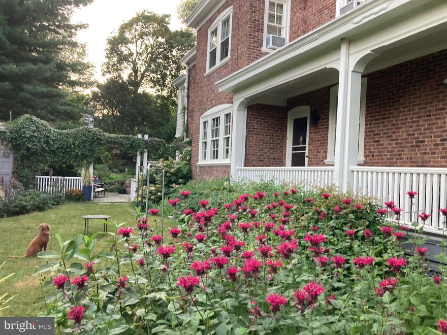 Victorian Twin Available in the Heart of Mt. Airy Village.

A rare offering in West Mt. Airy, this 2,328 sq. ft. light-filled, three-story twin sits on a south-facing double lot with a private driveway and garage. Magnificent spruce trees provide exceptional privacy for this hidden gem, featuring 5 bedrooms, 2.5 baths, a chef’s kitchen, large laundry area, detached insulated 378 sq. ft. garage/workshop with heat and electric, a spacious patio, and a mature perennial garden.

This classic 1907 Philadelphia twin has been meticulously maintained and thoughtfully modernized by its architect-owner. Original windows, storms, cornice, and trim are in excellent condition and freshly painted. The home features its original slate mansard roof along with newer membrane roofing.

Light-filled rooms with windows on two sides face east, south, and west across the 7,750 sq. ft. lot. Original oak floors with mahogany detailing have been freshly refinished, and original interior doors, moldings, and hardware are freshly painted. The home features comfortable, quiet hot water radiator heat with functioning valves in all rooms.

The spacious living room, dining room, and kitchen create inviting areas for everyday living and entertaining. Living and dining spaces are separated by a demountable cabinetry screen designed by the architect-owner in a tasteful mid-century style. The functional fireplace features a large bluestone hearth and glass tile surround.

The kitchen continues the mid-century aesthetic with a five-burner cooktop, restaurant-quality hood, large oven, stainless steel counters, mosaic glass tile backsplash, custom cabinetry, and an eat-at butcher block island. Ample storage includes full-extension drawers and generous pantry cabinets. A heated mudroom and powder room are located at the rear entrance.

The second floor offers two large bedrooms, including one with an oversized walk-in closet leading to a glass-enclosed sleeping porch. A beautifully renovated mid-century-inspired full bath features a large shower, double sinks, herringbone basalt tile flooring and accent wall, and a custom concrete counter. The front bedroom, currently used as a writing office, features a built-in desk within a bay window and ample shelving potential. A large linen closet completes the hall.

The third floor includes three cozy, light-filled bedrooms with full closets, along with a hall closet and a charming full bath featuring the original clawfoot tub.

The private wrap-around porch, elevated from the street, includes a 20-foot 19th-century Quaker bench. The fenced backyard is terraced, with a large patio of reclaimed bluestone sidewalks, dry-laid schist walls, and a mature perennial garden with native and exotic plantings.

The location is truly unbeatable! At the end of the block, enjoy all the amenities of Mt. Airy Village, including Weavers Way Co-op, sought-after C.W. Henry School, Carpenter’s Woods, High Point Café, and more. Easy access to Center City via the Chestnut Hill West line or bus routes #71 and #23.

This is a truly special home on an exceptional lot, in a prime location, surrounded by a vibrant and welcoming community.