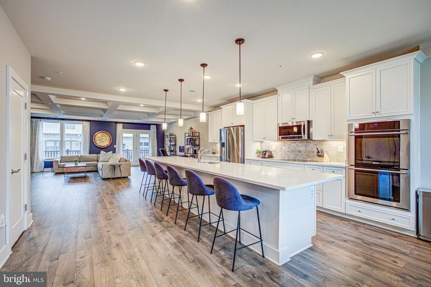 A must-see upper level condo in the Metro Square community - less than a quarter mile from the new Herndon-Monroe Silver Line stop! This unit features over 2500 square feet of living space, plus a one-car garage, a large balcony on the main level, and a private rooftop patio.  The main level offers plenty of space and amenities for entertaining with its open concept living/kitchen/dining area, 16 foot long kitchen island (yes, really), quartz countertops, upgraded appliance package with induction cooktop and double wall oven, and beautiful white soft-close cabinetry. Upstairs, the primary bedroom has a huge walk-in closet and bathroom with a frameless glass rain shower and upgraded cabinetry. Two additional bedrooms feature ample closet space, and all have easy access to the laundry room centrally located on the upper level. Continue up the stairs to reach your private roof patio with expansive east/west facing views. The owners also added enhancements such as custom brick work in the living room and front entry, custom Elfa closet/storage systems in all three bedrooms and the garage, smart features such as Nest thermostat and doorbell, Lutron lighting in the living room, and a Tesla charger in the garage! Close to "downtown" Herndon, Worldgate Centre, Reston Town Center, and more... or enjoy quick access to the Dulles Toll Road to Tyson's Corner, Ashburn and beyond. Note, the listing agent and spouse own the property.