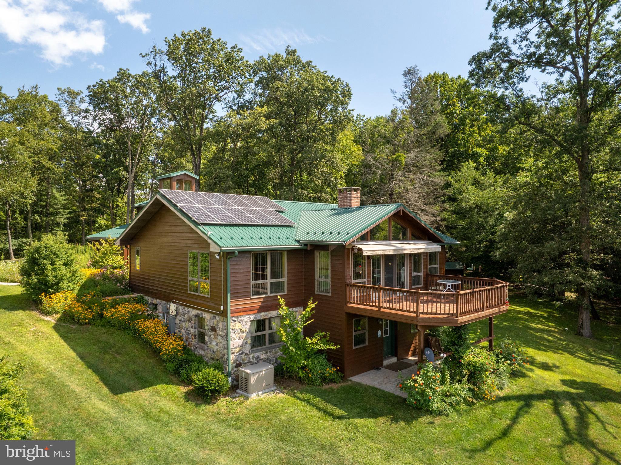 Welcome to a place where timeless beauty, thoughtful design, and the wonders of nature come together to create something truly special. Tucked away at the end of a winding driveway with mature apple trees, this extraordinary 173 acre estate invites you into a world of peace, privacy, and refined country living. Surrounded by the lush canopy of Central Appalachian oak pine forest, the property offers gently rolling hills, wildflower meadows, and streams are pristine, including the Conewago Creek, that create a landscape as enchanting as it is expansive. Explore your own apple orchard, hike through woodlands filled with chestnut oak, hickory, and red maple, and enjoy the sights and sounds of native wildlife including deer, wild turkeys, red-tailed hawks, foxes, and woodpeckers. Whether you’re on foot or horseback, the trails offer year-round enjoyment. Protected by a conservation easement, this property is as enduring as it is beautiful. At its center is a well-maintained home designed to bring the outdoors in and elevate everyday living. Offering three bedrooms and two and a half bathrooms, the home blends comfort and craftsmanship throughout. A sun drenched vaulted sunroom with panoramic views and hardwood floors welcomes you with warmth. The adjacent kitchen combines rustic charm and modern convenience, featuring pine inset cabinetry, glass front displays, engineered hardwood floors, and a walk in pantry with laundry, utility sink, and ample storage. The home’s layout supports both gathering and relaxation. The dining room glows with natural light, while the spacious family room features vaulted ceilings, a wood burning fireplace and heatilator, plush carpeting, and sliding doors that lead to a large deck with 13 foot retractable awning, perfect for enjoying nature year round. A dedicated home office offers custom built hickory cabinetry and recessed lighting, ideal for remote work or focused creative time. The main level primary suite includes crown molding, a cedar lined walk in closet, and an inviting ensuite with a walk in pebble stone shower, marble flooring, and warm, organic finishes that reflect the home’s natural surroundings. The daylight walkout lower level offers additional versatility with two more bedrooms, a luxurious full bath, a second office or flex space, and a tile floored recreation room with a wood burning stove. Outdoor living features include a covered patio, expansive deck, a three-car garage with overhead storage, and a private architectural feature: a watchtower above the garage offering panoramic views of the surrounding landscape, an ideal spot for observing nature or stargazing. Complementing these features are owned solar panels and geothermal heating and cooling, providing energy efficiency and sustainability. A large Morton building offers extra storage, while a whole-house Kohler generator, powered by a 500-gallon buried (and owned) propane tank, ensures comfort and reliability year-round. This is more than a home, it's a rare property offering natural beauty, modern comfort, and the opportunity to steward a truly special piece of land. Schedule your private tour today.