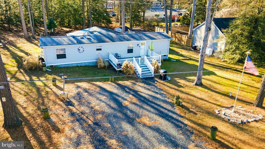 Welcome to this inviting home featuring a large, brand-new front deck, perfect for relaxing or entertaining. Step inside to a bright living room with luxury vinyl plank flooring that flows seamlessly into the kitchen, complete with stainless steel appliances. A spacious four-season room offers year-round enjoyment and flexible living space. The home includes two comfortable bedrooms and one and a half bathrooms. Situated on a generous .34-acre lot that backs to trees, the property provides privacy and a peaceful setting. Located in Angola Neck Park with no HOA fees, this home offers freedom and flexibility. Enjoy the convenience of being near Lewes and Rehoboth beaches, miles of coastline, outlet shopping, dining options galore, entertainment venues, grocery stores, pharmacies, and medical services. The property also features ample parking for up to six vehicles plus an RV water and sewer hookup conveniently located next to the house. This is coastal living with space, comfort, and unmatched accessibility.