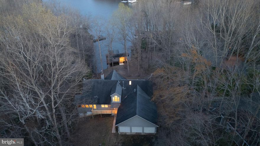 Nestled on the public shoreline of Lake Anna, this classic lake home is a promising property. It's perfectly situated on 1.60 acres of prime waterfront, and 140 feet of shoreline. The home offers over 5,600 square feet of living space, 4 bedrooms, and 4.5 bathrooms. As soon as you enter the home, you're greeted with breathtaking lake views. The main living space is bright and airy, with floor-to-ceiling windows, a see-through fireplace, and an enclosed hot tub room where you can relax and enjoy the serene lake views. The primary suite is located on the main level, with an attached ensuite. The expansive main level also features a second bedroom with an attached bath, a business-sized office, an open kitchen, and a sunroom with a pellet stove to keep you warm as you overlook this peaceful property.
Upstairs, you'll find two more bedrooms, a full bathroom, and a loft sitting area that overlooks the main living area and the lake views. The full basement has an open rec/living area with a grand stone fireplace encompassing the entire wall, a walk-out patio, and more lake views. You'll also find another full bath, a storage area, and a walk-out patio in the basement. Though the charm of the lake house is undeniable, time has left its mark, urging for a touch of modernization and renewal. 
This home's outdoor living is perfect for lake life, with a 400-square-foot rear deck that spans the length of the home. There's a three-car garage and an additional detached garage that provides ample room to store your boat and water toys. Enjoy lake days lounging at the boat house with a covered deck and an enclosed slip with a roll-up door for security.
With a dash of creativity, a sprinkle of vision, and a bit of love, this lake house holds the key to becoming a sanctuary of serenity and beauty, a place where new memories will be woven into the fabric of its walls. You'll also be just minutes away from shopping, multiple dining options, and a host of events. High-speed internet is available as well. This property is a must-see!