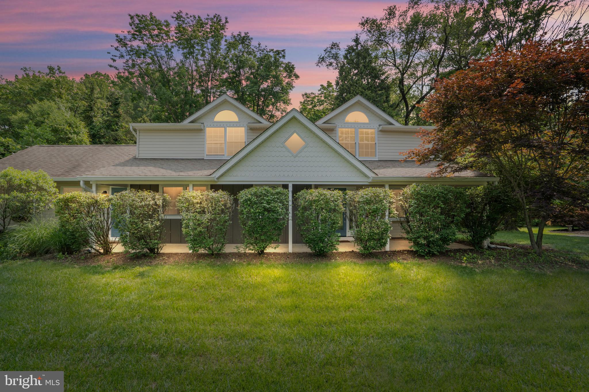 Nestled at the end of a peaceful cul-de-sac in the heart of the highly desirable Pebble Hill community, this character-filled 5-bedroom, 4.1-bathroom residence offers timeless charm, abundant natural light, and remarkable versatility—including a private, light-filled first-floor in-law suite. From the moment you arrive, this home captivates with dormer windows, a sprawling front porch, and undeniable curb appeal. Step inside to discover a welcoming open-concept layout enhanced by gleaming hardwood floors, sunlit living spaces, and an inviting nook for keeping the chef company. The kitchen evokes refined cottage style with its crisp white cabinetry, stainless steel appliances, oversized center island, farmhouse sink, and cozy built-in bench seating. Tucked just off the main living area, the sunny in-law suite is a true sanctuary with its own en suite bathroom, closet space, and expansive picture window offering serene views of the backyard—ideal for multigenerational living or extended guest stays. On the lower level, the great room is anchored by a classic brick wood-burning fireplace and framed by large windows that bring the outdoors in. It’s the perfect space for entertaining or unwinding, complemented by a stylish powder room, oversized laundry area with custom maple cabinetry, mechanicals, and additional storage. Upstairs, the spacious primary suite is a peaceful retreat, featuring unique architectural details, updated ceiling fans, and not one but three walk-in closets. The luxurious en suite bath boasts a walk-in tile shower, natural light, and a chic, modern vanity. Three additional generously sized bedrooms, all bathed in natural light and outfitted with ample closet space, share two updated full baths. Step through the sliding glass doors to a fully fenced backyard oasis—ideal for gardeners and outdoor enthusiasts alike. Enjoy raised garden beds, a large shed, and a greenhouse ready for seed-starting. The private patio offers a tranquil space for relaxing, surrounded by nature. Additional features include an oversized two-car garage, a state-of-the-art water filtration system, and a newly installed septic system (2023), providing peace of mind and practical upgrades for modern living. With its rare blend of warmth, space, and flexibility—all in a private and picturesque setting—this home is a must-see in one of Doylestown’s most beloved neighborhoods.
