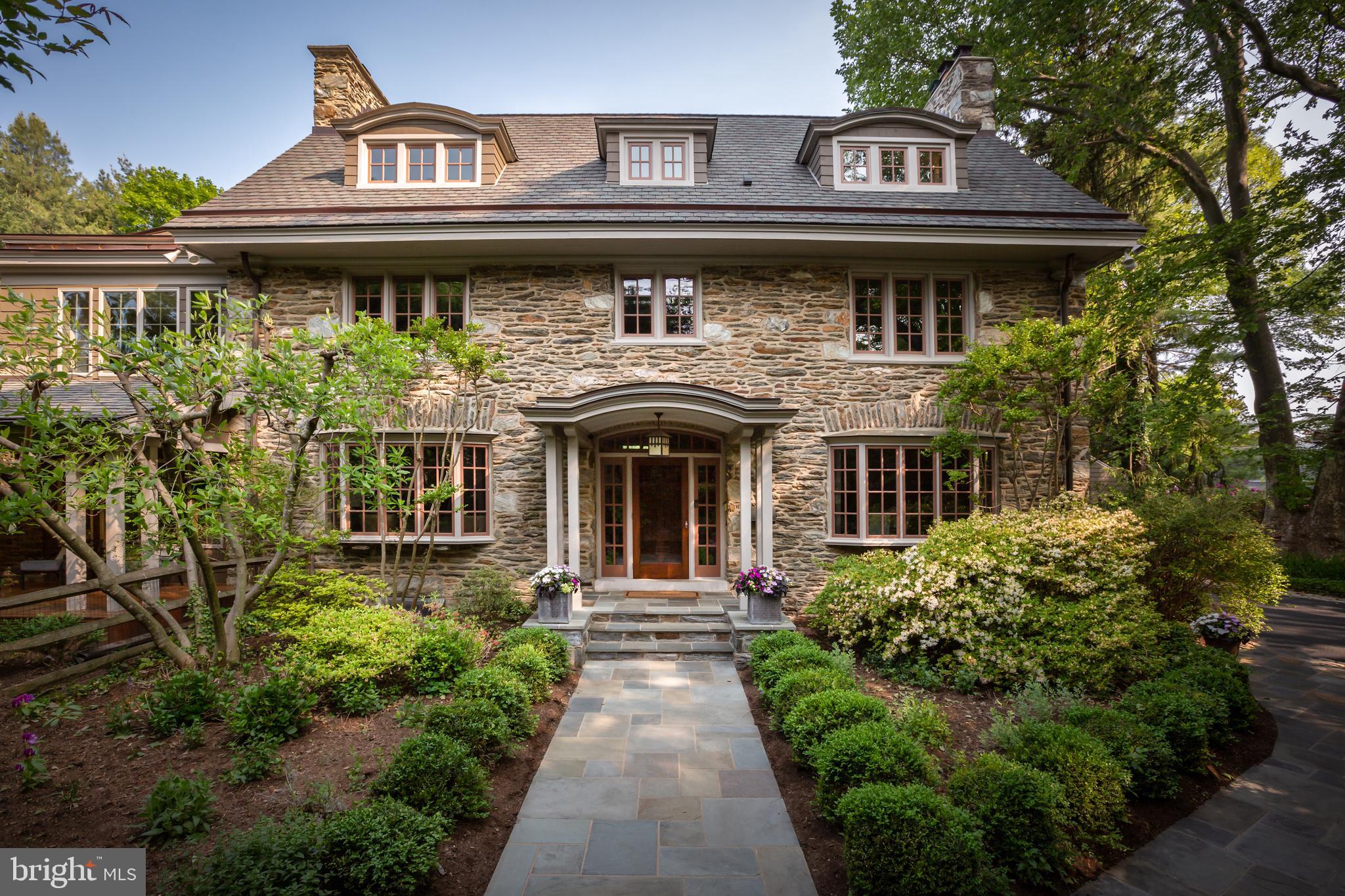 Located at the end of a private lane, this magnificent Cotswald-style, stone manor home was designed and built in the early 1900’s and meticulously reconstructed inside and out in the early 2000’s by the current owners. Combining all the grace and stately presence of the early 20th century with the style and function of today, this home is perfection. This 3-story Center Hall home features 5 Bedrooms, 4.5 tile Baths, generous room sizes and millwork, 4 gas fireplaces, beautiful hardwood floor, a chef-worthy Kitchen, a large professionally landscaped private lot, 3 zone HVAC, circular driveway, wine cellar, whole house generator, and a separate 3-car Garage. All this in a “walk-to-Wayne” location and award winning Radnor Township Schools. The traditional floor plan features hardwood floor with a stenciled border in the oversized Center Hall, fireside Living Room and fireside Dining Room. The Family Room includes multiple windows and french doors leading to a gracious, mahogany-floored Veranda. The Kitchen includes a commercial-style gas range, all stainless appliances, pickled wood cabinetry, granite counters, a wine fridge, ice machine, and a center island. A separate Breakfast Room, Breakfast Deck, Mud Room, back stairs and a rear entrance with barrel ceiling complete the first floor. Access the 2nd floor via a turned staircase. The Main Suite includes a spacious Sitting Room with ornate stone, gas fireplace and leads to the Main Bedroom with three walls of windows overlooking the lovely landscaped gardens. The Main Bath features a marble tile shower, jetted tub and two separate vanities. The 2nd Bedroom has a brick, gas fireplace and extensive cherry built-ins. A marble tile Hall Bath with stall shower, a separate Laundry Room and a room-size Cedar Closet complete the 2nd floor. The 3rd floor has wall-to-wall carpeting, 3 Bedrooms, a marble tile Hall Bath with a stall shower and a pedestal sink, and a 2nd large Cedar Closet. The exterior features include unique Wissahickon schist stone construction, a circular driveway edged in Belgian block, flagstone walkway, stone pillars, field stone Terrace, a wrap-around Philippine Mahogany Veranda, a rear yard edged in evergreens, professionally landscaped gardens with mature plantings, extensive exterior lighting and a sprinkler system, and a 3-car detached Garage with its own HVAC and walk-up second floor storage attic. Walk to Wayne and have dinner and enjoy all the amenities and shopping options that the Main Line has to offer.