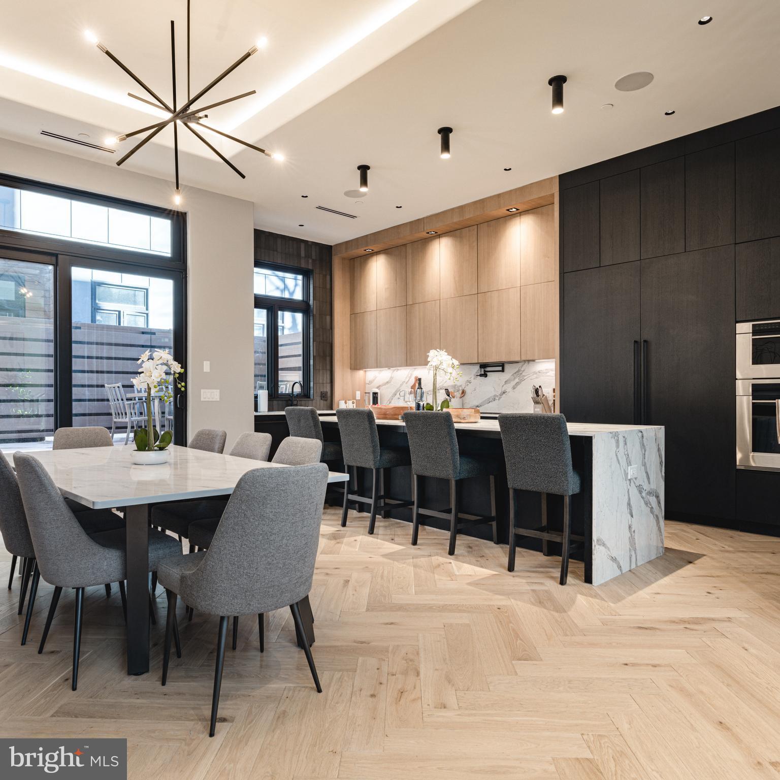 Welcome to The Residences at Extrava — an exclusive gated community redefining upscale urban living in the heart of Philadelphia’s prestigious Fitler Square neighborhood. This expansive 5,300+ square foot home blends sophisticated design with exceptional functionality and is being offered fully furnished, making it truly turnkey. Set on a quiet block, these 28-foot-wide homes offer an extraordinary sense of space and volume rarely found in the city. Featuring 4 generously sized bedrooms, 4 full bathrooms, 2 powder rooms, and a private 3-car garage with soaring 13-foot ceilings—ideal for car lifts and up to 6-car capacity—this home was designed with the modern luxury buyer in mind. A six-stop elevator services every level, from the dramatic double-height foyer to the show stopping rooftop deck with panoramic skyline views and a private hot tub. Interior finishes were curated in collaboration with Gnome Architects, J. THOM Design, and Zatos Investments, resulting in a seamless blend of modern conveniences and local craftsmanship. Rich herringbone hardwood flooring, custom white-oak floating staircases, and expansive walls of glass define the main living level. The kitchen is a chef’s dream—outfitted with Sub-Zero and Wolf appliances, imported Mobalco cabinetry from Spain, a quartz waterfall island, hidden butler’s pantry, and tray-ceiling dining area. A lofted den level provides incredible flexibility—ideal for entertaining, working from home, or relaxing—featuring a wet bar, metal slat accent wall, and glass railing system. Upstairs, two guest bedrooms include private en-suite baths and walk-in closets, while a dedicated laundry room features full tile work, built-in shelving, and a utility sink. The primary suite is a luxurious retreat covering an entire floor, complete with a wraparound balcony, wet bar, and fully customized California Closet. The spa-like bath boasts heated floors, dual rain showers, steam room, soaking tub, and floating dual vanities. Finally, the top offers the ultimate indoor-outdoor lifestyle: a sky lounge with powder room and wet bar that opens directly onto an oversized roof deck with a hot tub and unobstructed Center City and river views. Additional highlights include automated blinds on all windows, full Smart Home wiring, and a 10-year property tax abatement (ends 8/31/2034). Fitler Square is celebrated for its blend of historic charm and modern conveniences, with access to the Schuylkill River Trail, top-ranked schools including Albert M. Greenfield, major medical institutions, and the region’s top universities just minutes away. Extrava isn’t just a home—it’s a lifestyle statement.