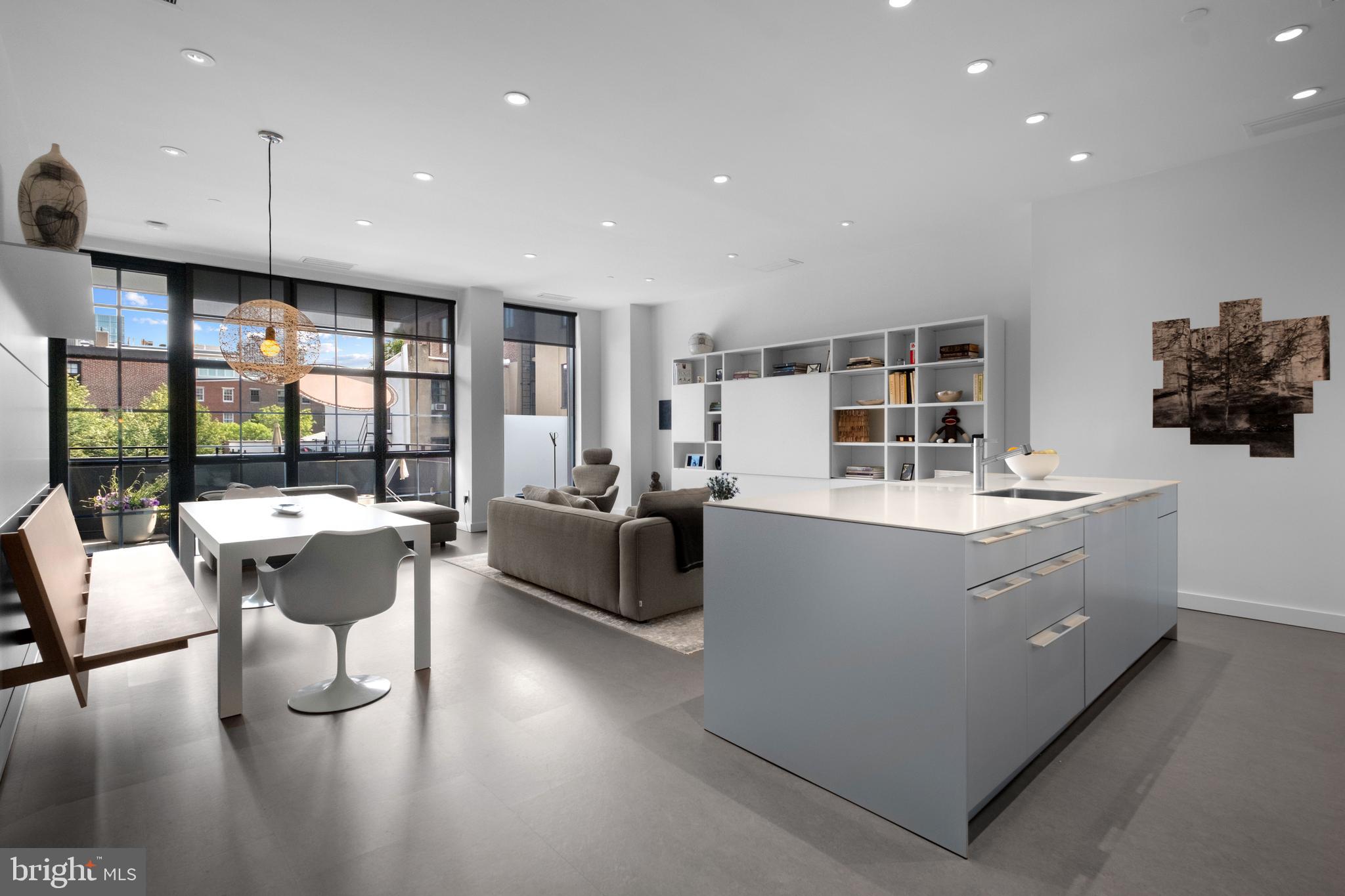 Elevated city living at 108 Arch Street, where striking architectural design by Brown/Hill meets the refined vision of acclaimed architect Wesley Wei. Residence 304 has been masterfully reimagined to embody modern luxury and timeless elegance, offering 1,406 square feet of open-concept sophistication.
A serene white palette, 10-foot ceilings, and oversized windows flood the space with natural light, creating a gallery-like ambiance throughout. At the heart of the home, a fully integrated Bulthaup kitchen features sleek white quartz countertops and premium Miele appliances—designed as much for culinary performance as for aesthetic appeal. Adjacent dining and living areas continue the curated experience, with custom wall treatments, built-in seating by Bulthaup, and a bespoke Italian bookcase and entertainment system by Lema, seamlessly blending form and function.
The spa-inspired bathrooms, with limestone tile and Raindance shower heads, offer a daily retreat. A covered, south-facing veranda invites quiet mornings or sunset cocktails, extending your living space into the open air.
With one deeded parking space, professional concierge service, and exceptionally low property taxes, this residence delivers the essence of sophisticated city living in a boutique, brick-and-zinc-clad setting in the heart of Old City.