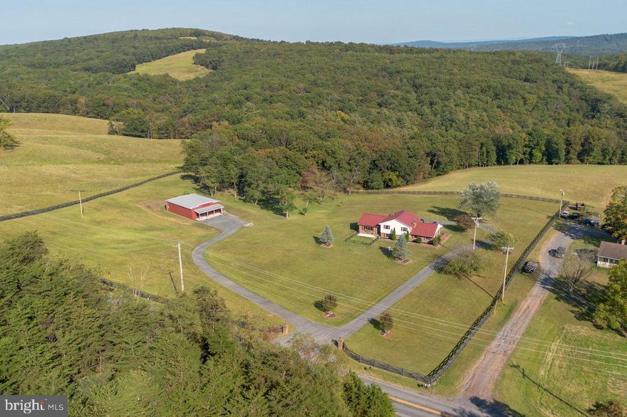 This charming split-level home, beautifully renovated in 2019, offers a perfect blend of modern comfort and classic appeal. Nestled on a generous 5.16-acre lot, the property boasts stunning panoramic views of the mountains and valleys, creating a serene backdrop for everyday living.  Step inside to discover an inviting open floor plan awash with natural light, featuring luxury vinyl plank and tile flooring that flows seamlessly throughout. The gourmet kitchen is a chef's dream, equipped with upgraded countertops, an island for casual dining, and high-end appliances, including a modern steam oven and built-in microwave. The spacious dining area opens seamlessly to the living room with a built-in serving station for cocktails to coffee.  A few steps away is the large family room with gas fireplace. With four well-appointed bedrooms and 2.5 bathrooms, including a primary suite with a walk-in shower, this home caters to all your needs. The fully finished basement offers additional living space, perfect for a home office or entertainment area. Outside, enjoy the expansive deck overlooking the beautifully landscaped yard, ideal for outdoor entertaining or quiet relaxation. The property features ample parking with an oversized garage and paved driveway, ensuring convenience for you and your guests. There is a 1800 sf shop with electric and separate paved drive and parking perfect for home based business, sports equipment, lawn equipment, crafts and hobbies, or workshop. This space is very flexible and accessible.  Located in a tranquil mountain setting, this home combines rural charm with easy access to local amenities. Experience the perfect blend of comfort, style, and nature in this exceptional property.